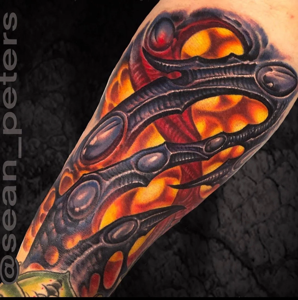 Colorful tattoo of a black octopus with detailed shading, set against a vibrant background of fiery orange and red flames.