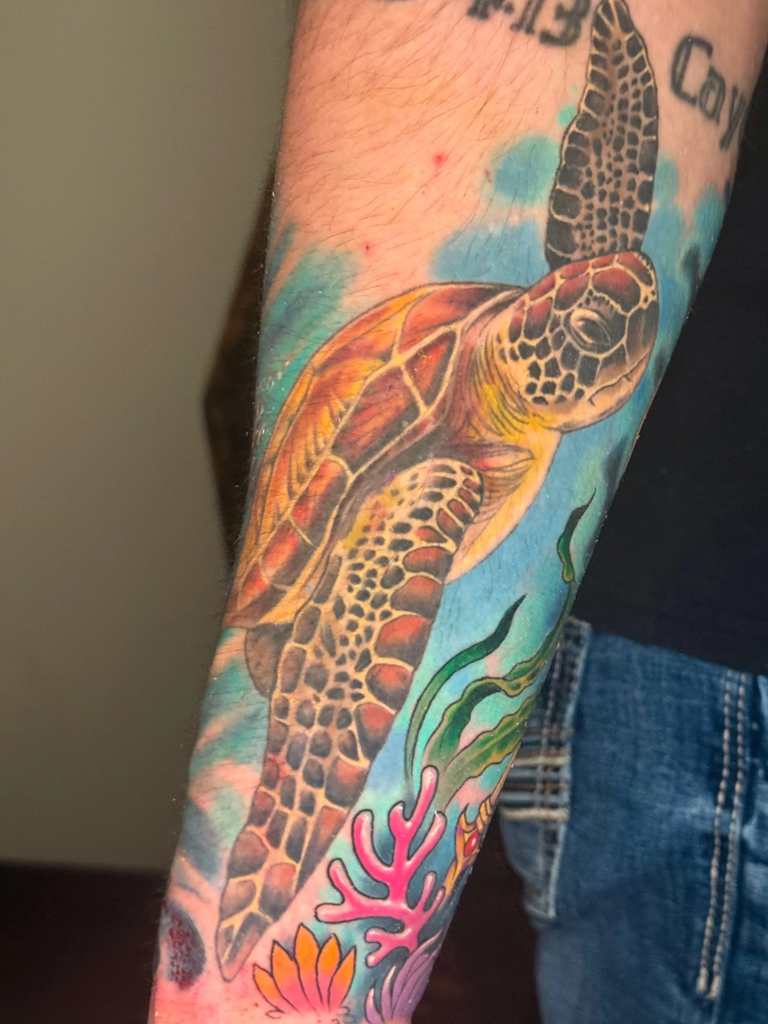 Colorful tattoo sleeve featuring a detailed giraffe and vibrant floral and abstract designs on a person's arm.