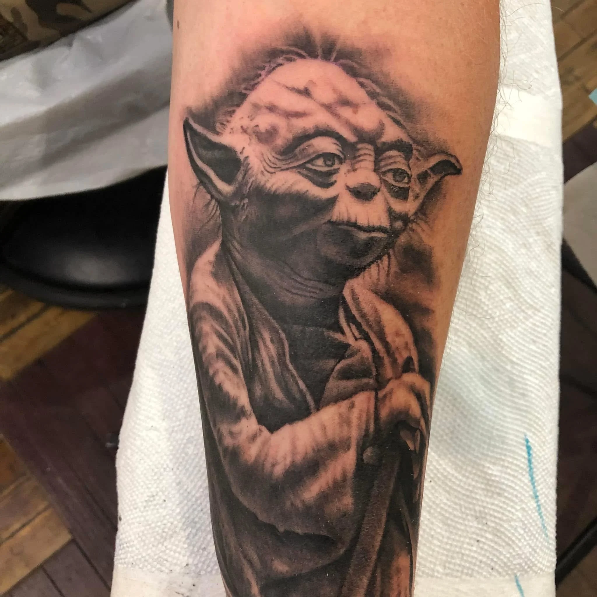 A tattoo of a clown face on a person's arm, showing detailed shading and facial features.