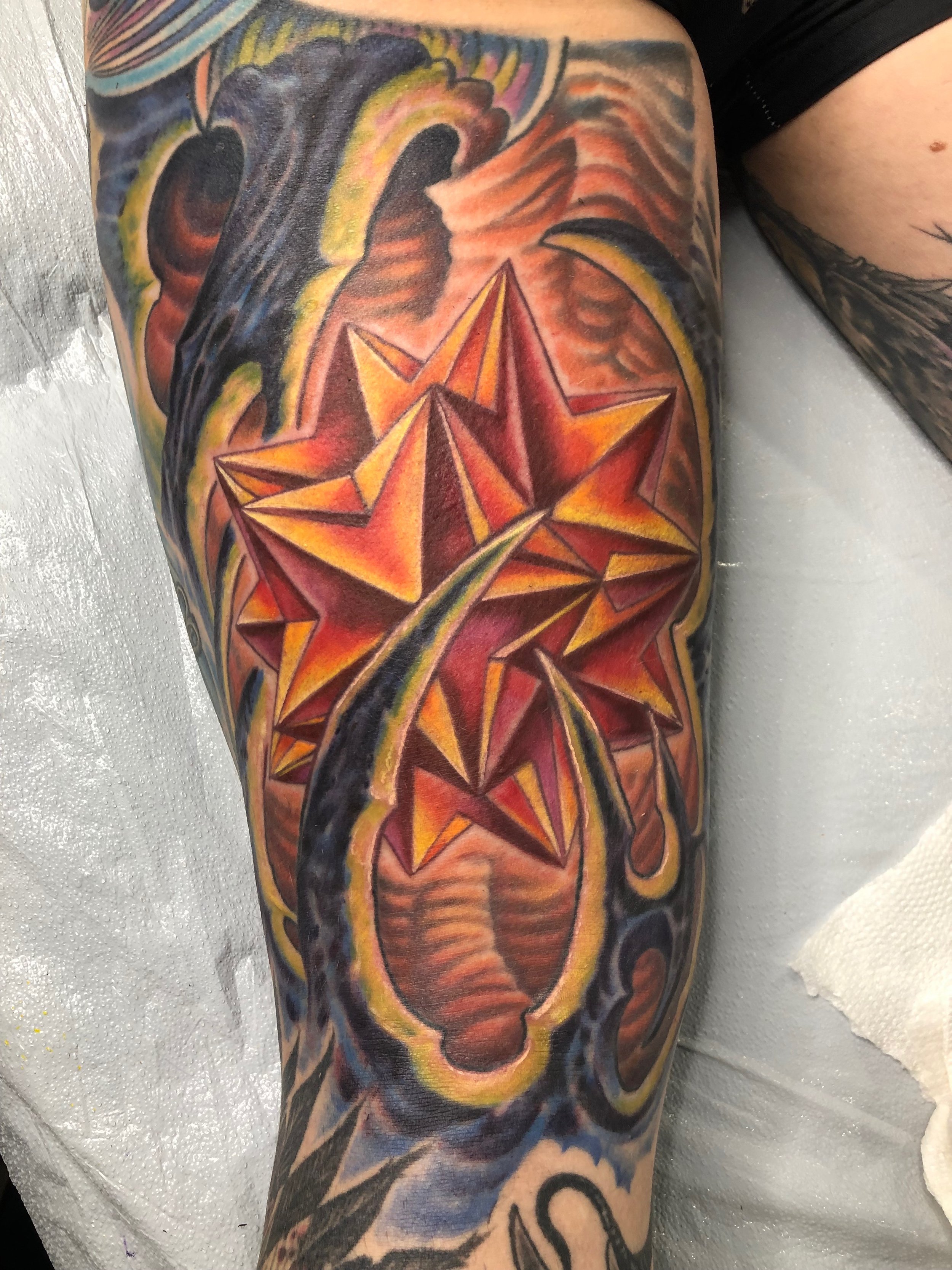 Close-up of a colorful tattoo on a person's arm featuring a star surrounded by vibrant, swirling colors.