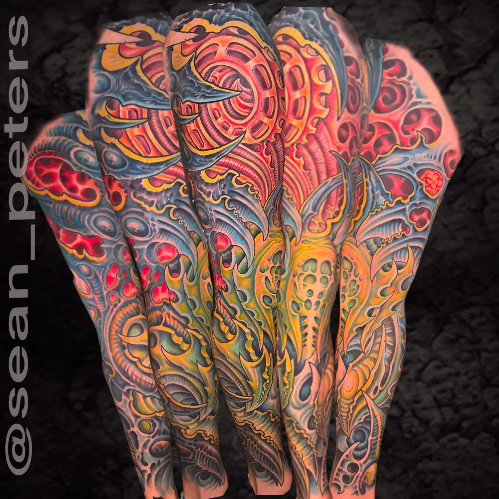 Colorful tattoos of marine creatures including sharks, rays, and jellyfish cover a person's arms and back, set against a black background.