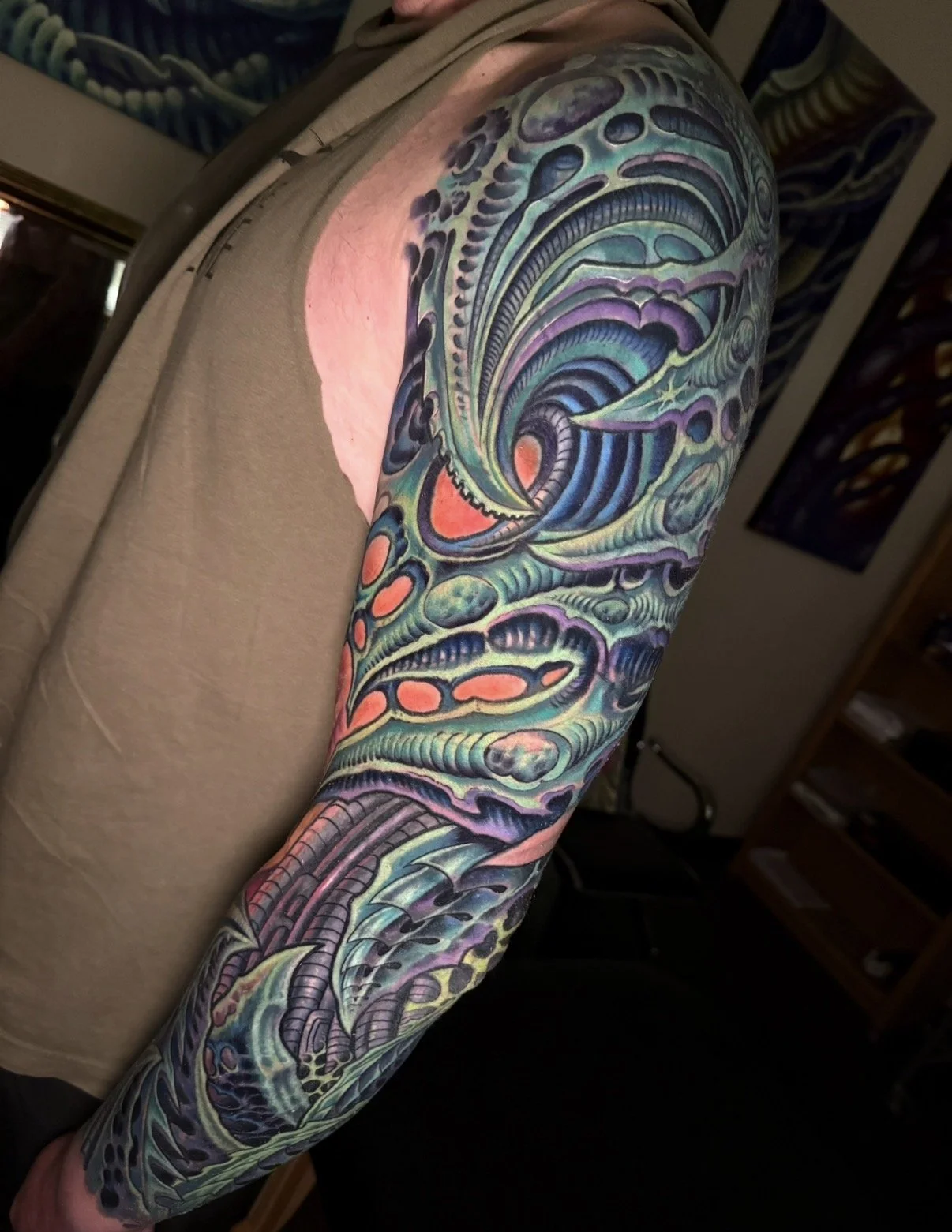 Colorful tattoo sleeve on a person's arm with abstract, oceanic, and cosmic design elements in vibrant shades of blue, purple, orange, and green.