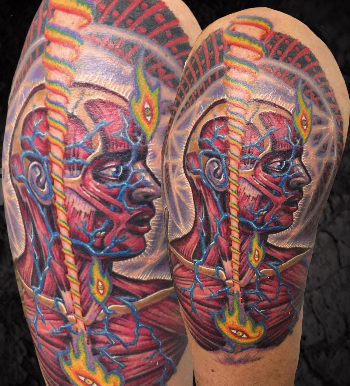 Colorful tattoo of a woman's face with a rainbow-colored snake and flames on both arms.