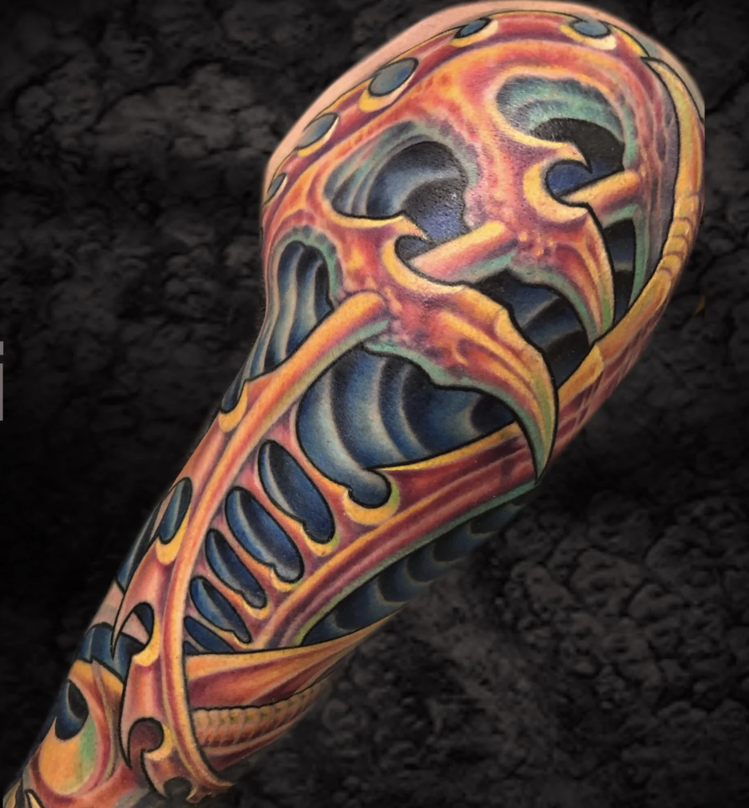 Colorful tattoo of a stylized skull with vibrant, swirling patterns on a person's arm.