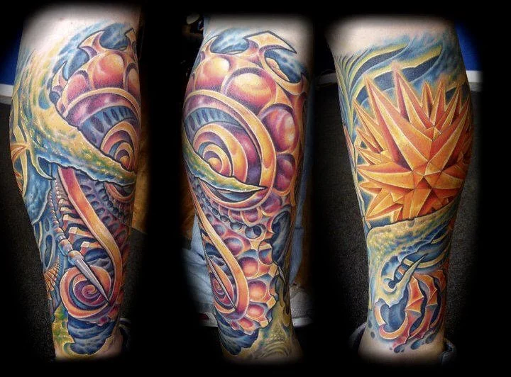 Colorful tattoo sleeve with abstract patterns, swirling shapes, and fiery geometric design on a person's arm.