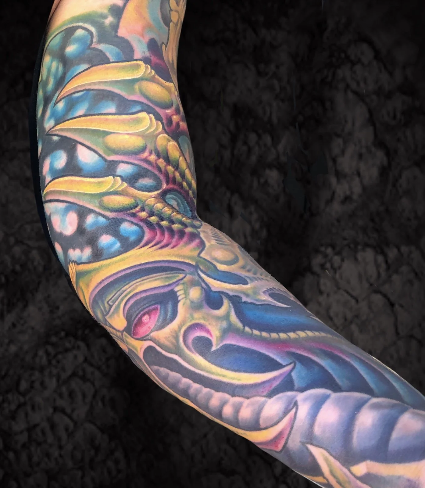 Colorful tattoo sleeve featuring abstract shapes and vibrant hues on a person's arm.