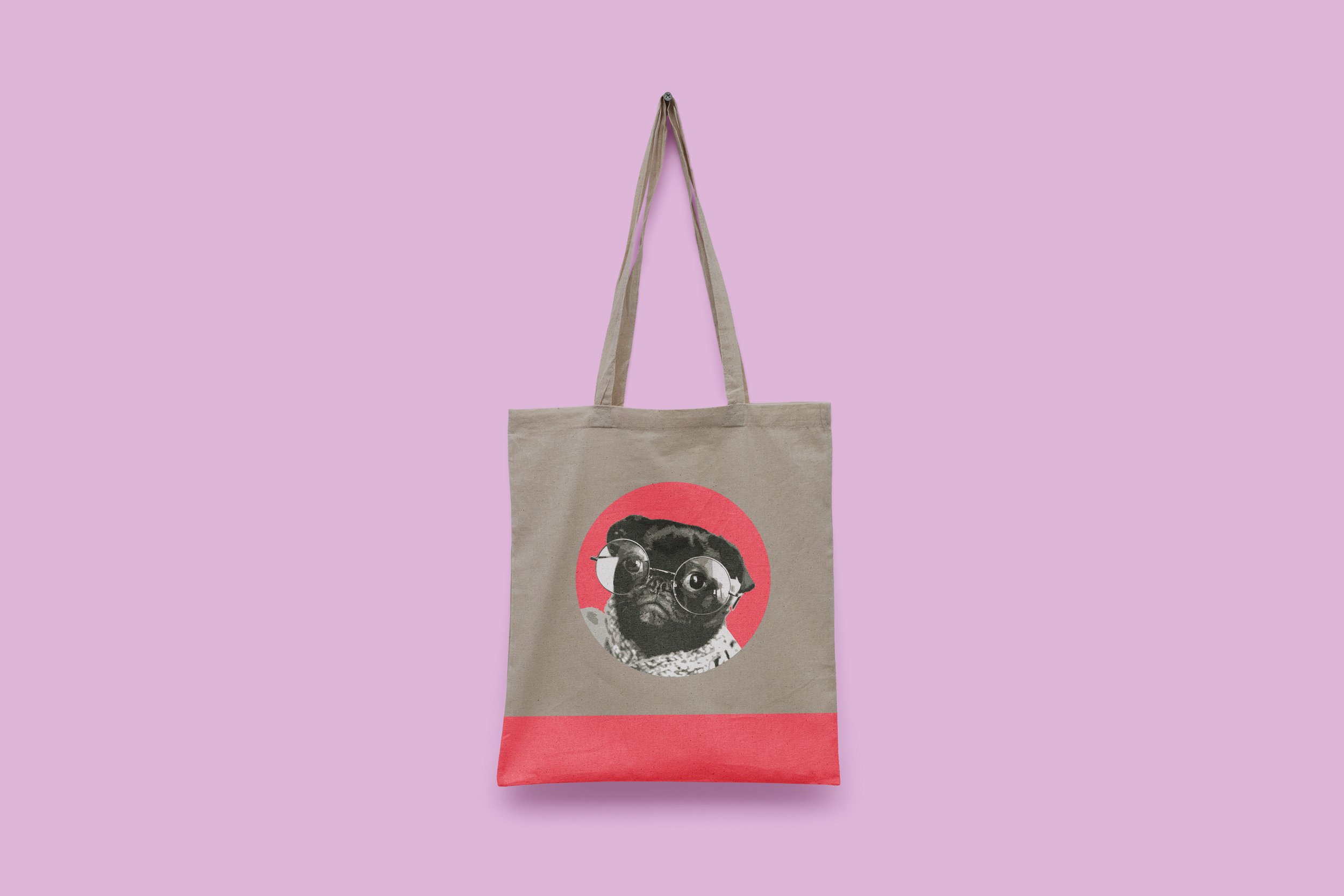 A beige tote bag with a graphic of a French bulldog wearing glasses inside a pink circle, with a red band at the bottom, hanging against a lavender background.