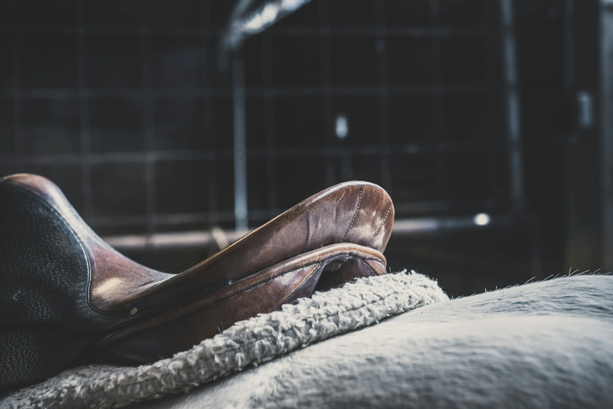 Close-up of vintage leather dress shoes resting on a textured surface with a blurred dark background.