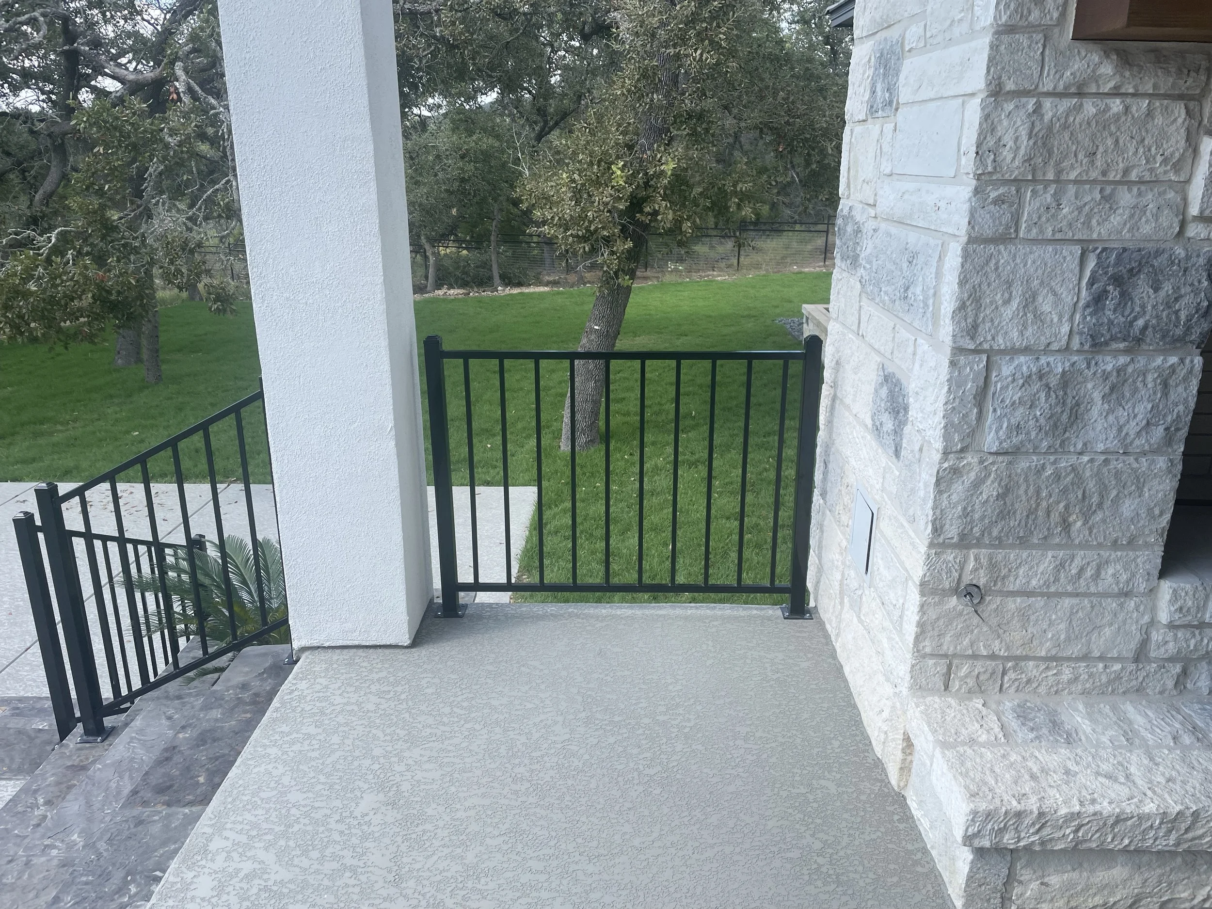 Black wrought iron railing on between house and rock pillar on back porch and black wrought iron railing on steps.