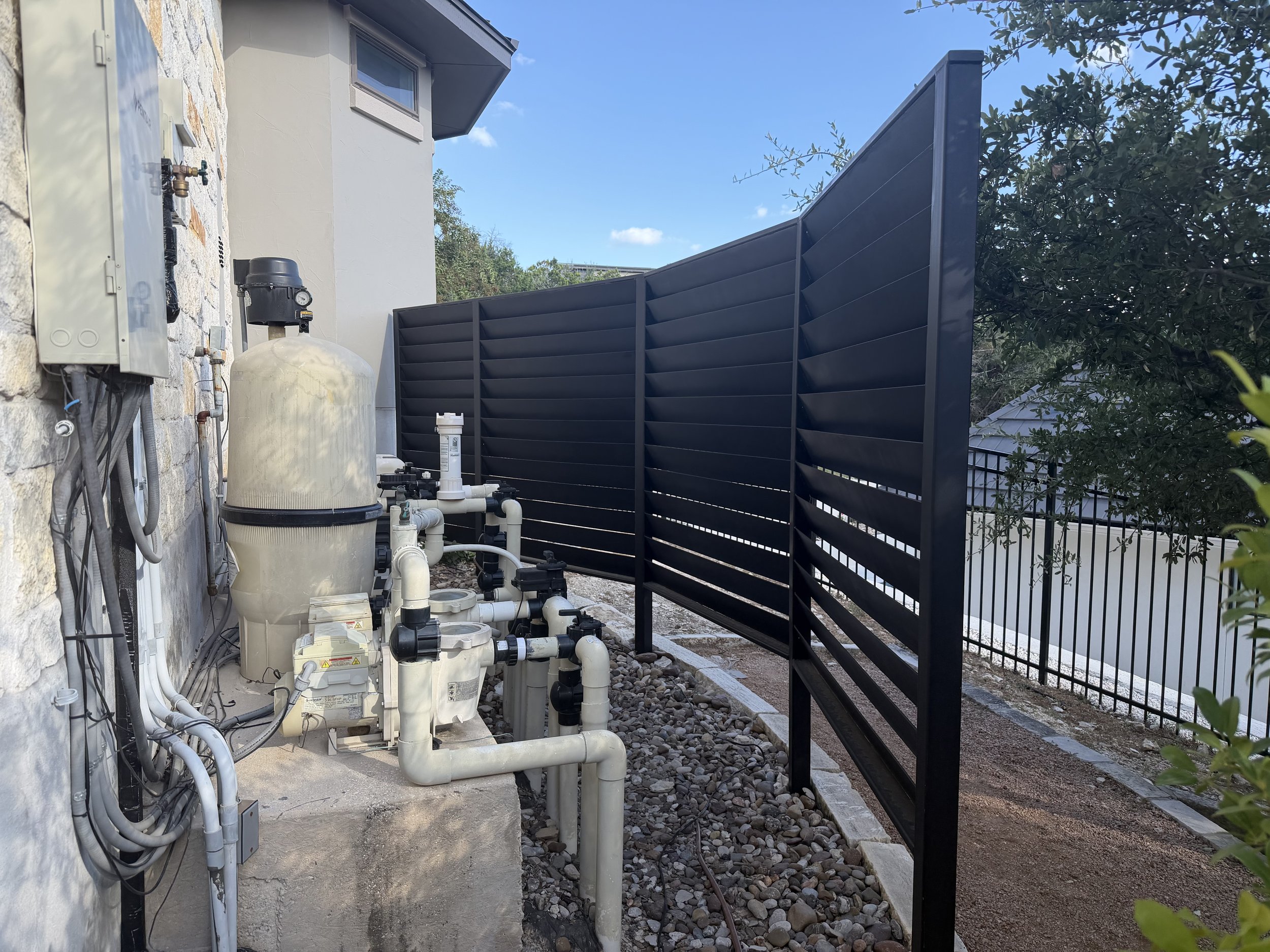 Screened metal louvered partial enclosure surrounding pool equipment.