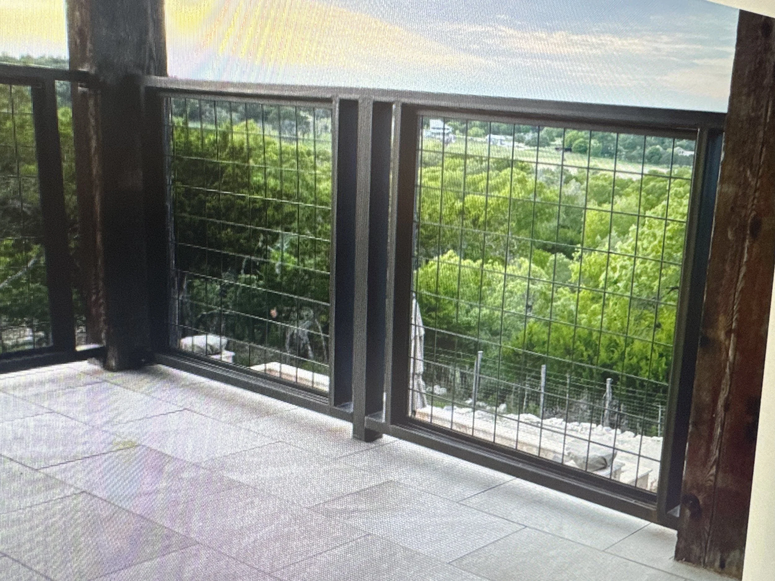 A metal square framed railing with paneling on a porch balcony.