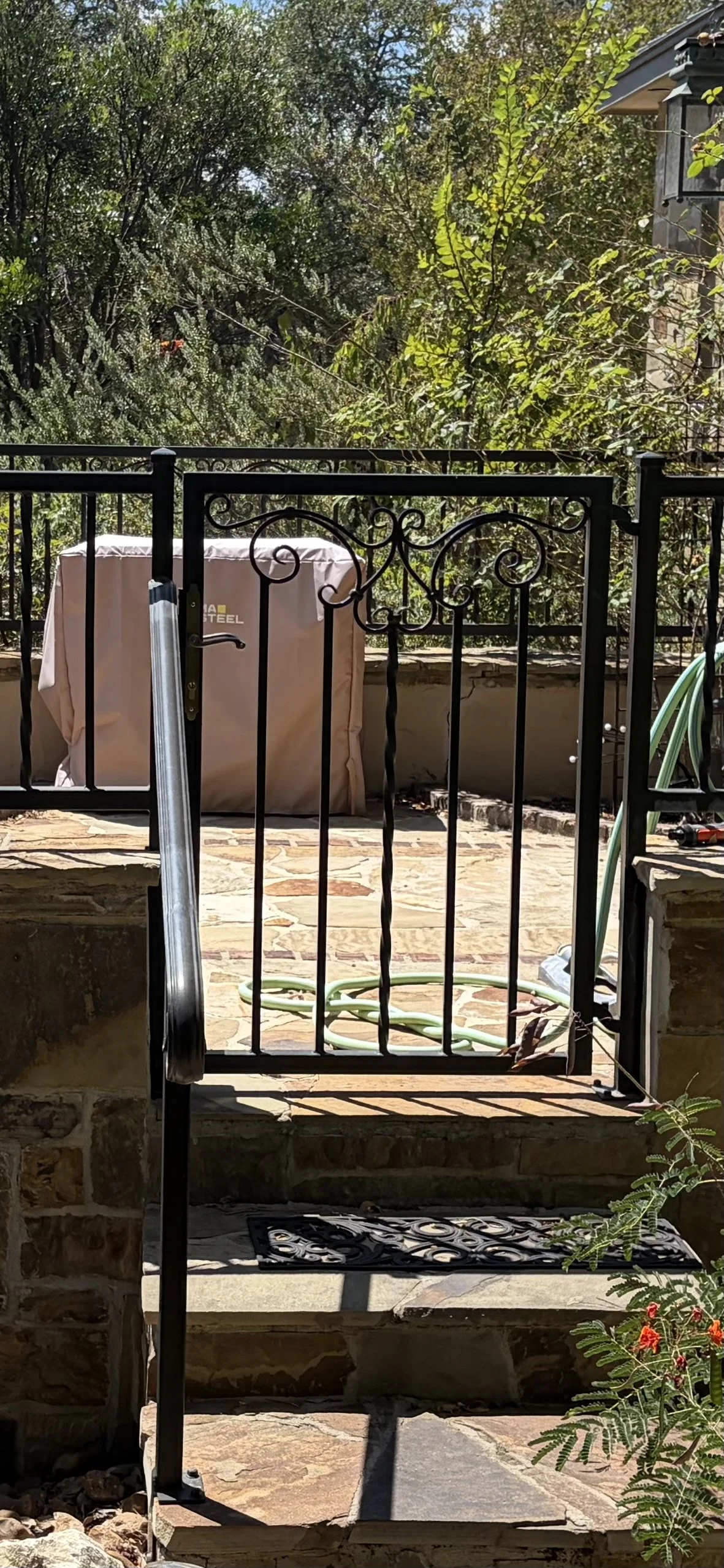  A ornamental wrought iron gate and hand rail in a small entry way leading to courtyard in front of stone house.