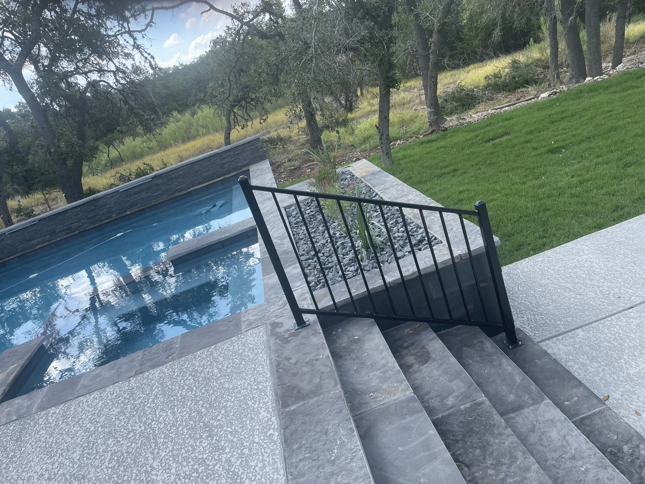 Black metal railing and steps by a pool.