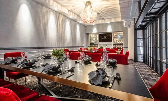 Donna Chang Mezzanine private dining room 3 with red chairs, wooden table set with glassware and cutlery, chandelier, and modern decor.