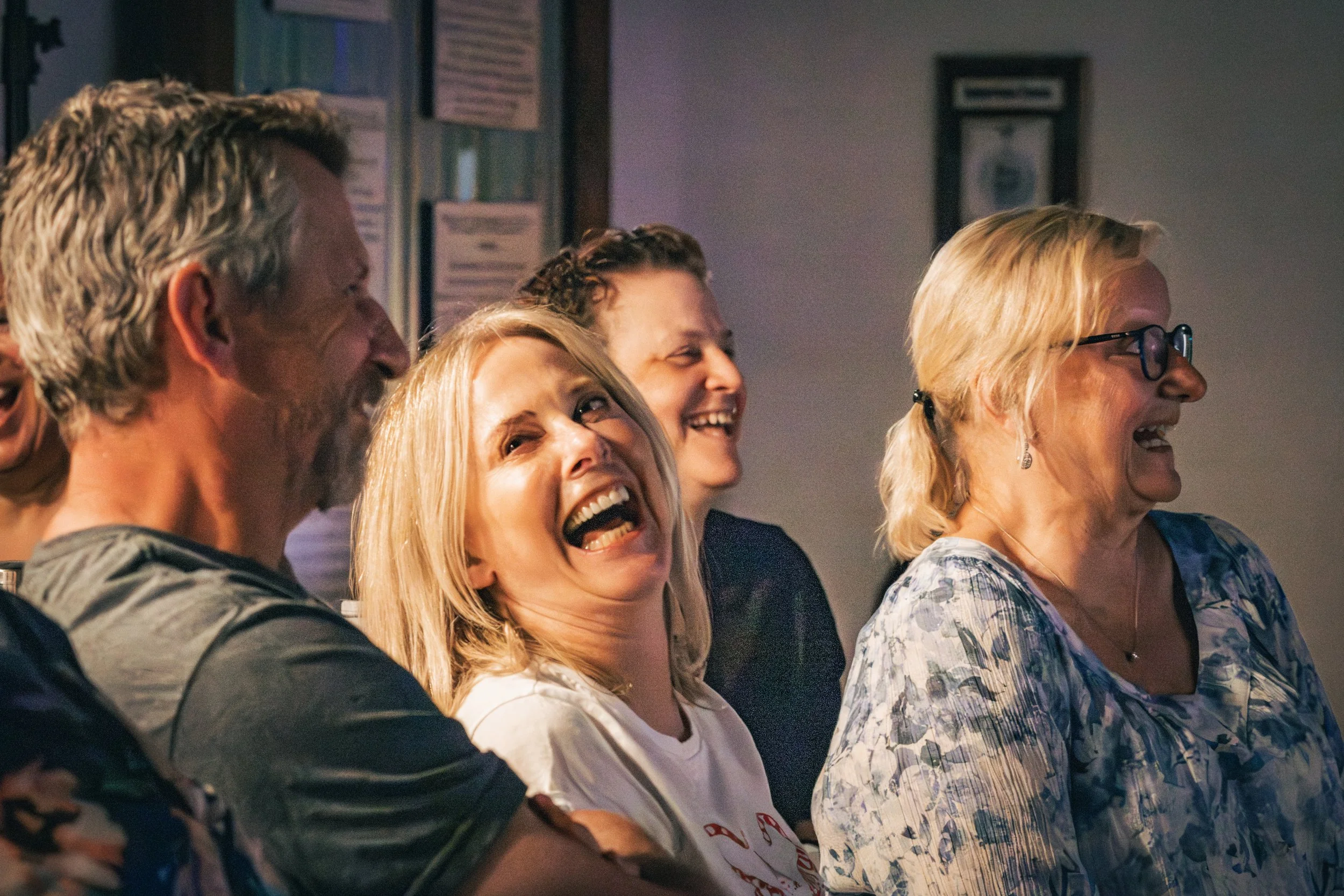 A group of people sitting in a row, smiling and laughing during an event or gathering.