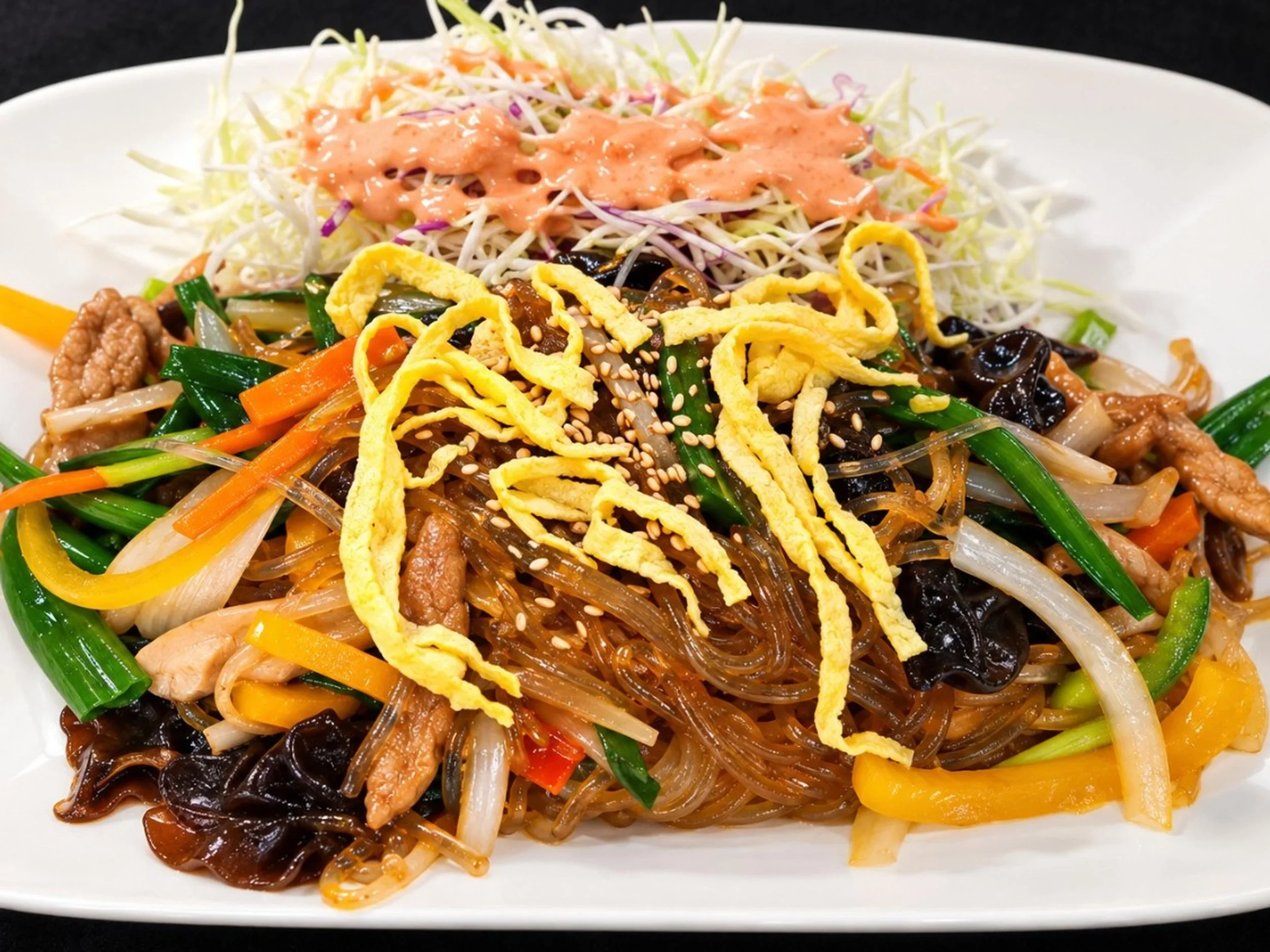 A plate of Asian stir-fried noodles with vegetables, topped with shredded egg, sesame seeds, and a pink sauce.