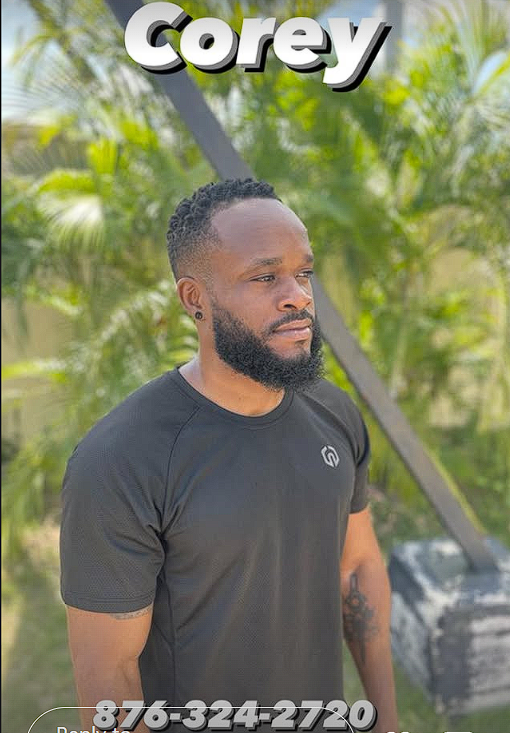 A man with a beard and short curly hair standing outdoors in front of green leafy plants, wearing a black t-shirt with a small logo on the chest, looking to the side with a serious expression. The text above his head reads 'Corey' in bold, 3D-style font. A phone number '876-324-2720' is at the bottom of the image.