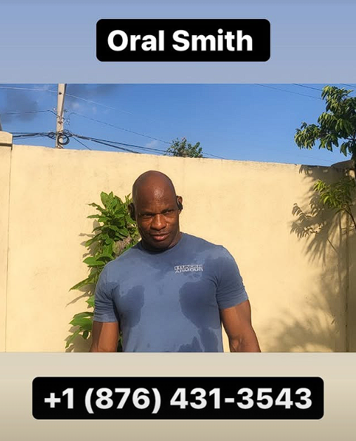 A man standing outdoors in front of a beige wall with green plants, wearing a blue Under Armour t-shirt, with a serious expression. Text overlay reads "Oral Smith" at the top and a phone number "+1 (876) 431-3543" at the bottom.