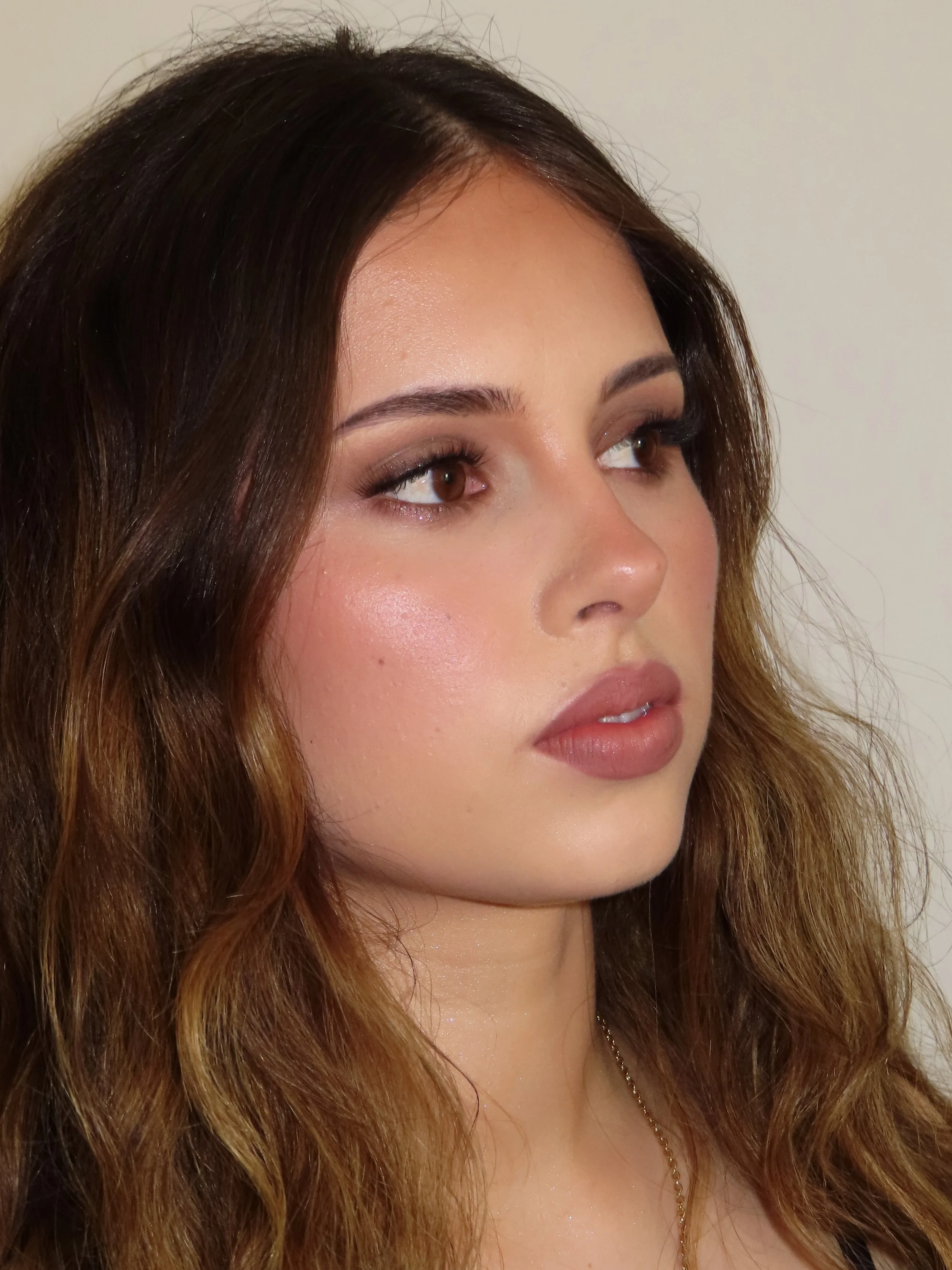 Close-up of a woman's face showing her brown hair, makeup, and jewelry.