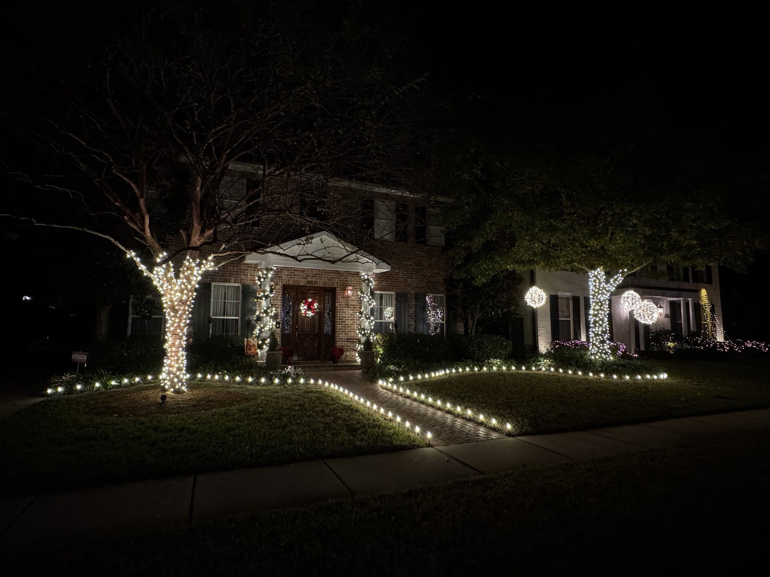 white-christmas-lights-brick-house-trees-pathway.jpg