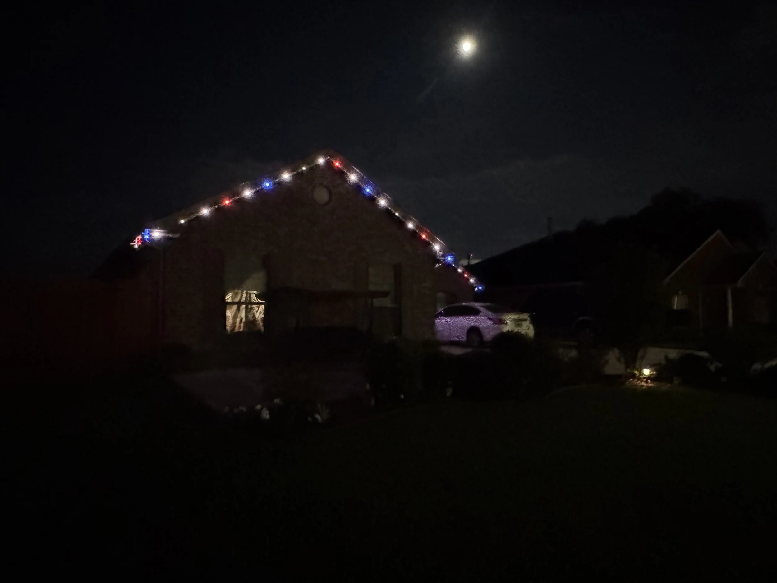 red-white-blue-lights-brick-home-roof-peak-at-night.jpg