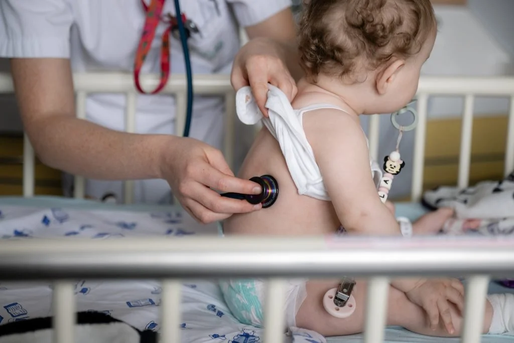 Médecin examnant un jeune enfant à l'hôpital avec un stéthoscope sur le torse