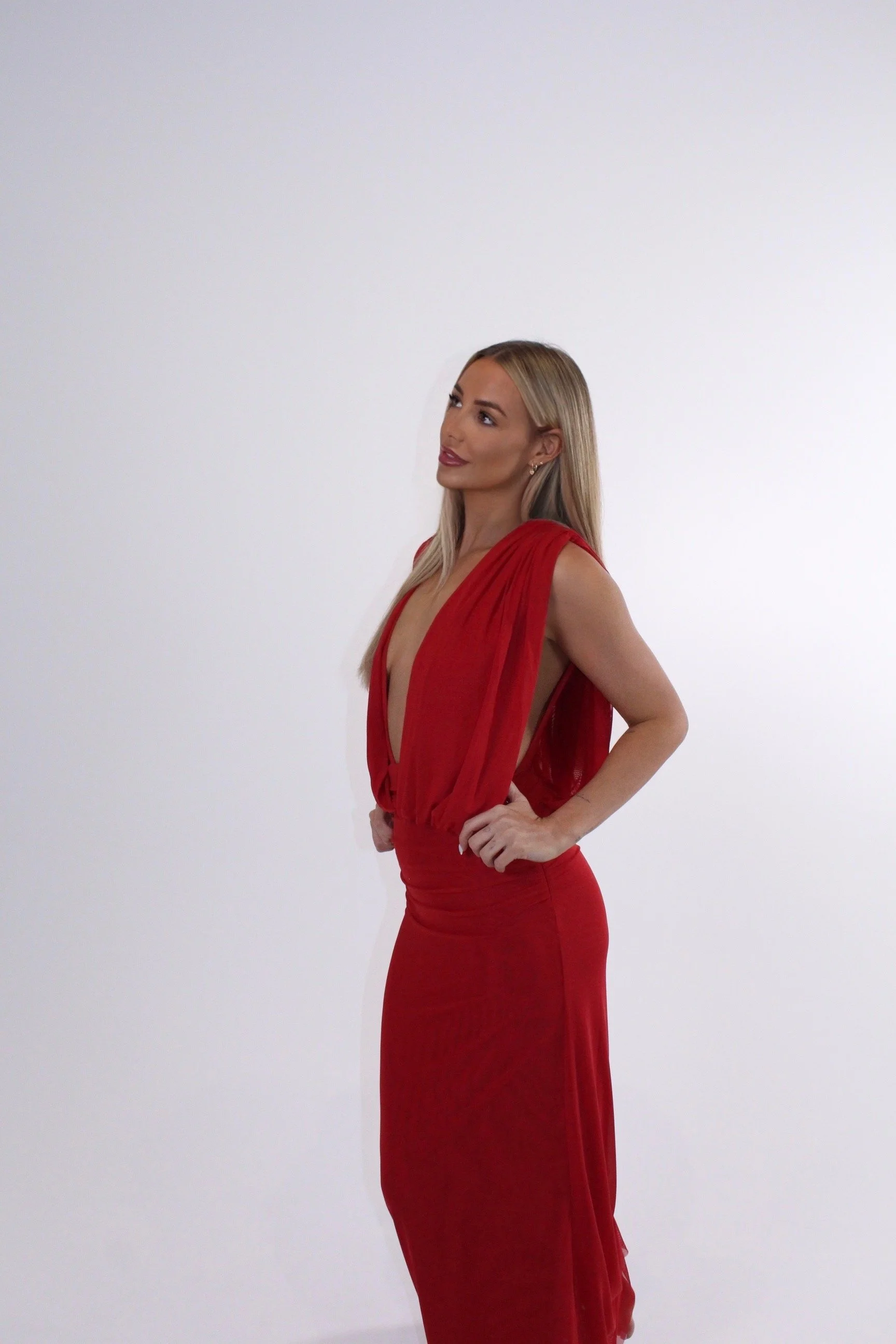 Blonde woman posing in a flowing red dress against a white background