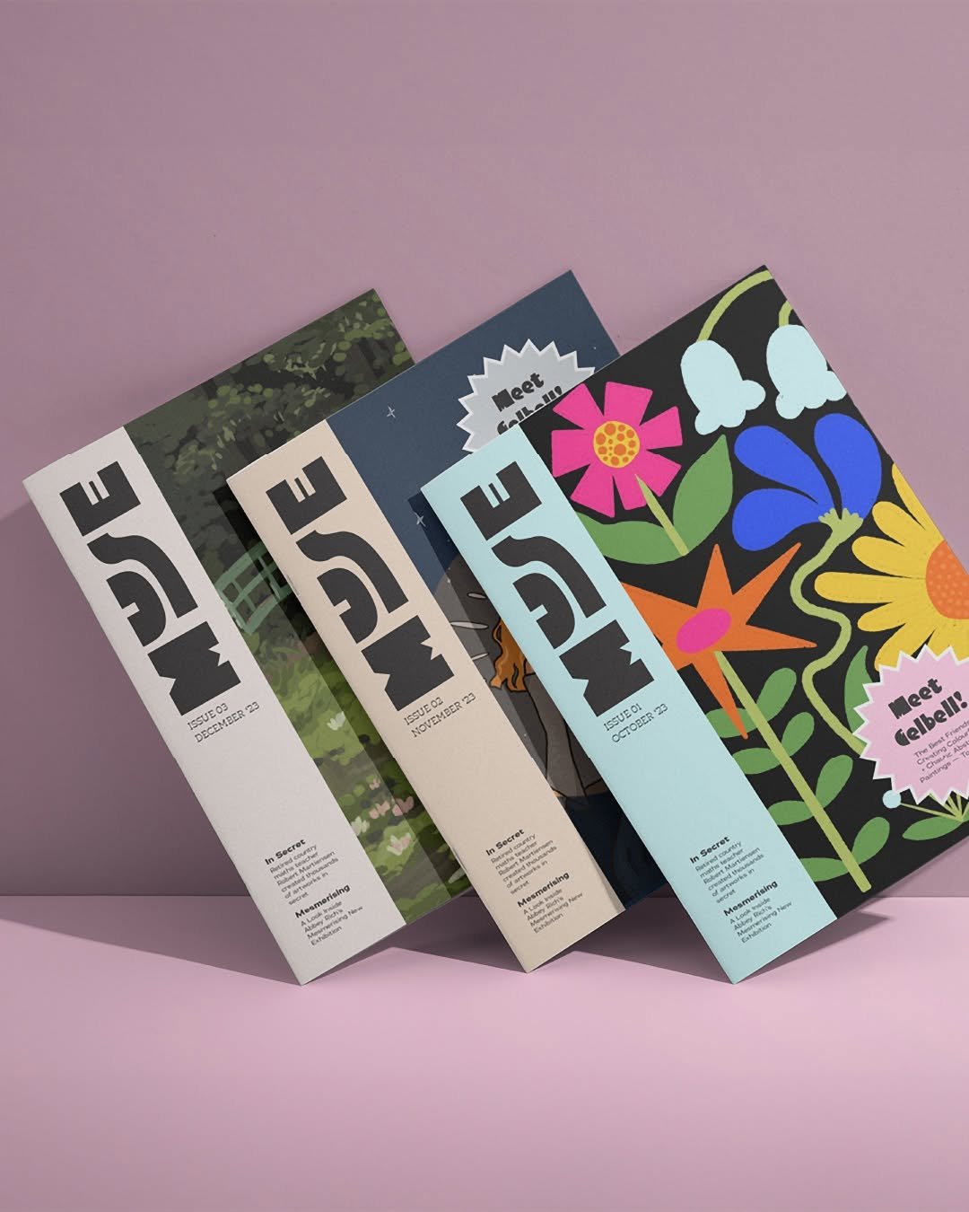 Four magazines with colorful covers, fanned out against a pink background.