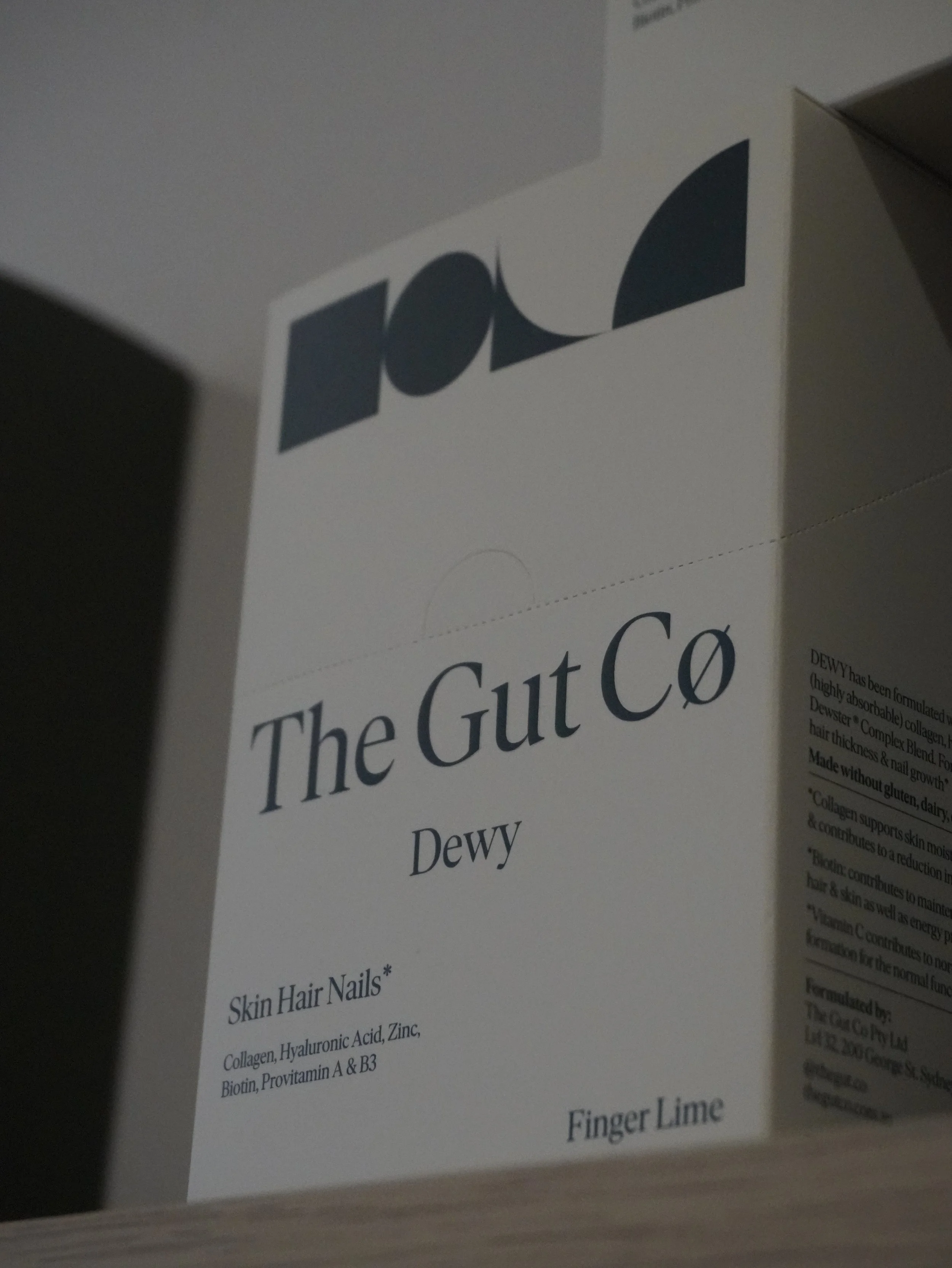 Close-up of a product information sheet titled 'The Gut Co.' with sections describing benefits for skin, nails, hair, and digestion, containing detailed descriptions and ingredients.