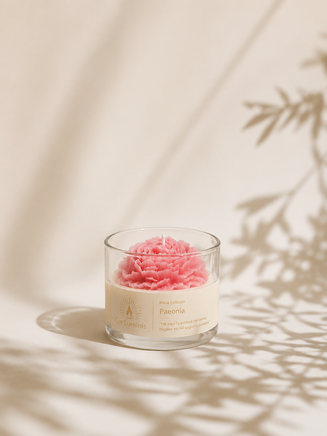 Vela decorativa con forma de flor en cera rosa en un recipiente de vidrio transparente sobre fondo beige, con fondo suave y minimalista.
