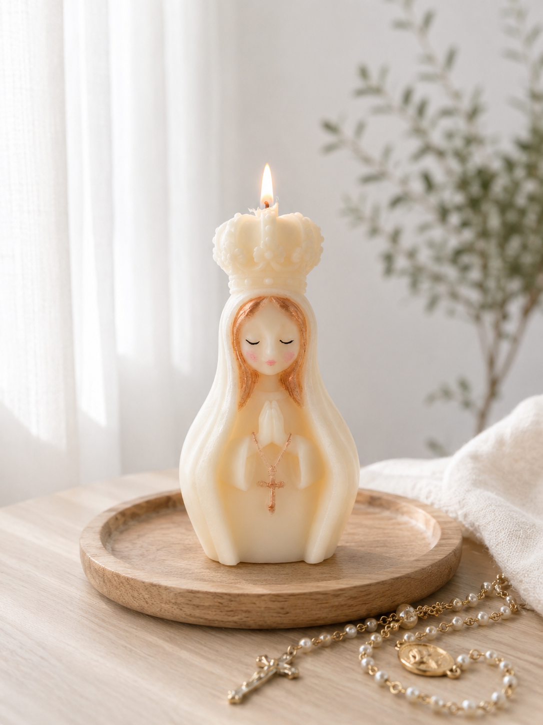 Vela de la Virgen María con una corona, y la vela encendida, en una bandeja de madera, con rosarios y tela blanca al lado, en un ambiente con luz natural.