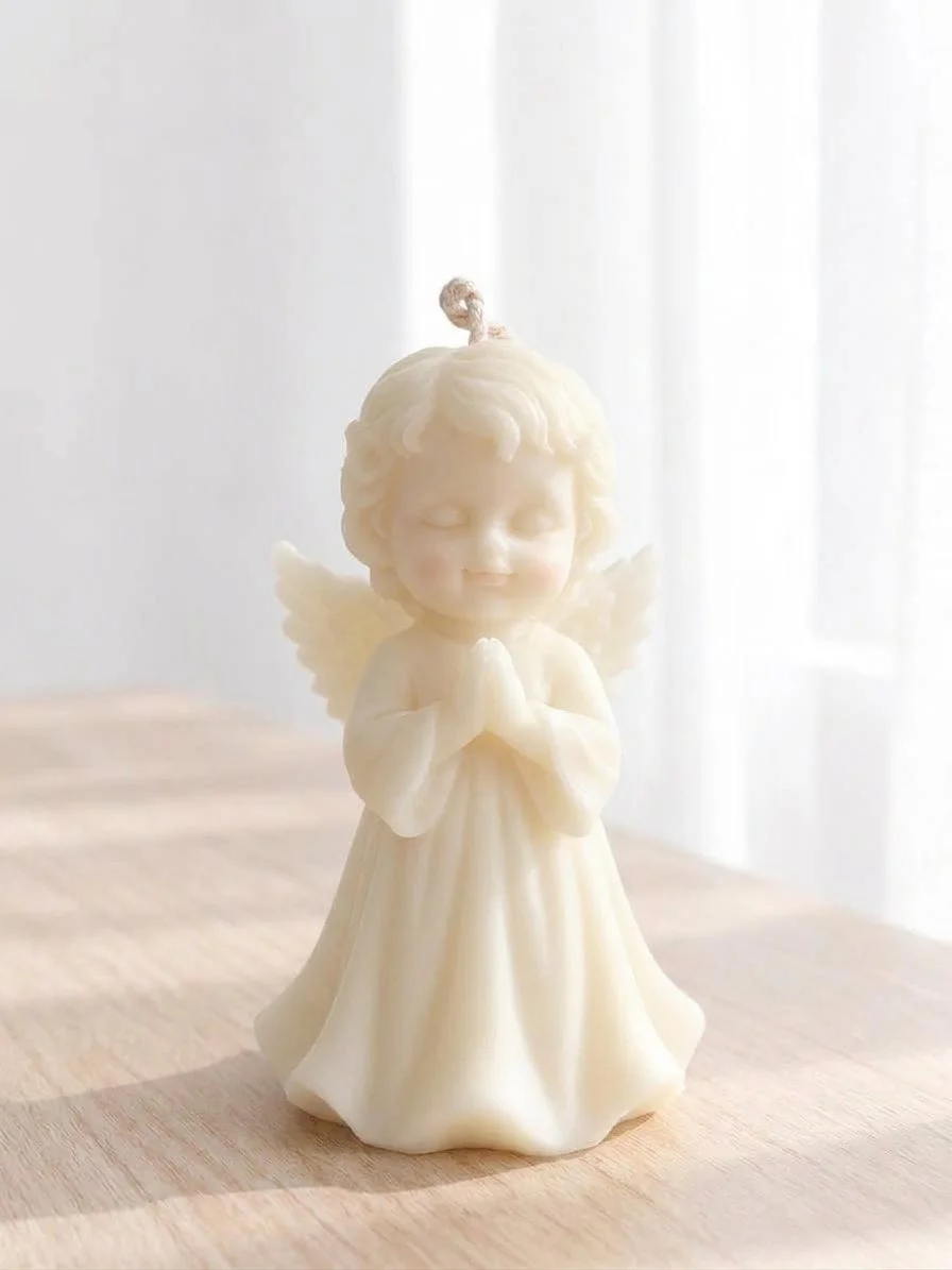 Figura de cera de un ángel con las manos en oración, cabello rizado y alas, en un entorno con luz suave.