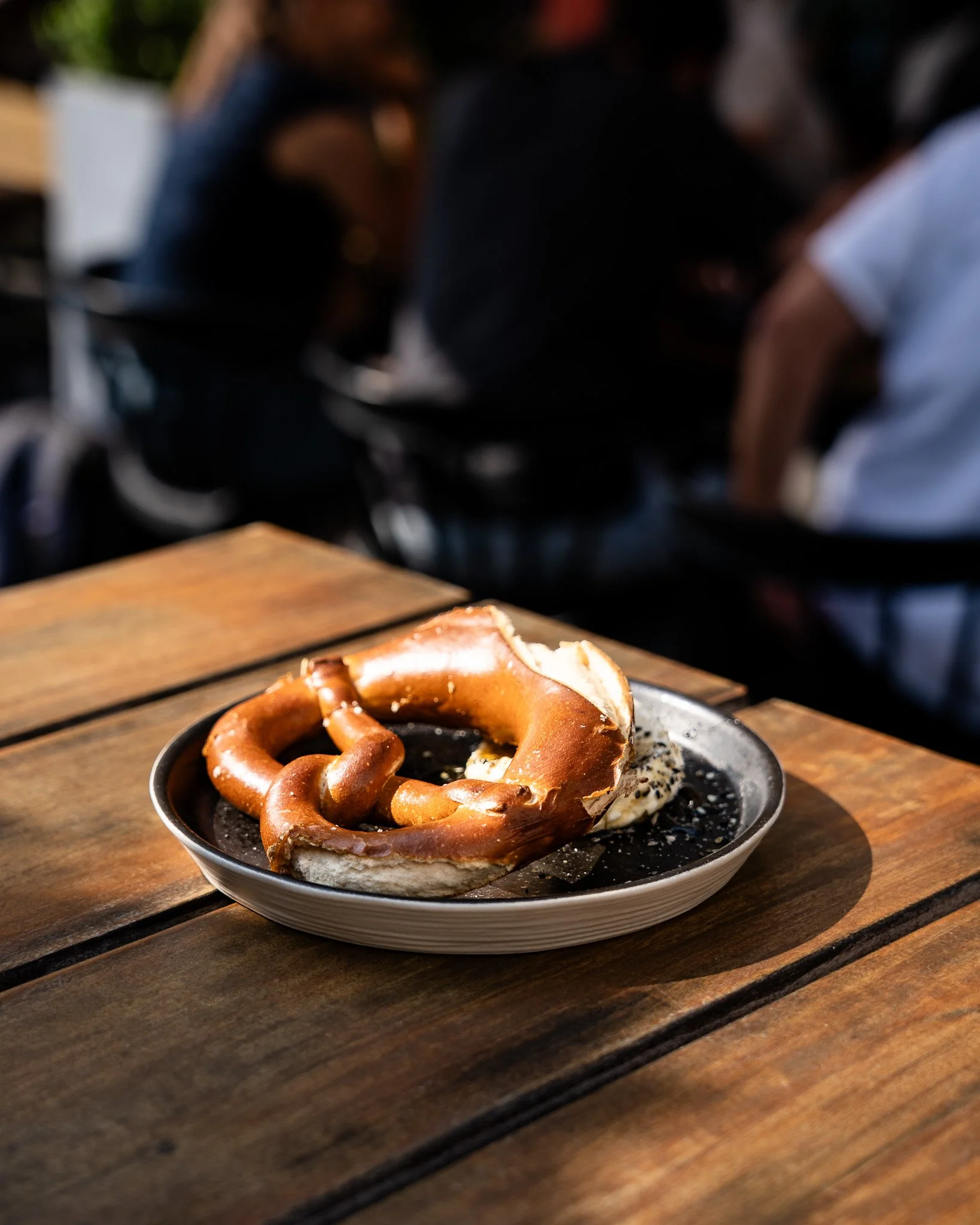 A plate of dessert with a pretzel on top, served on a wooden table.
