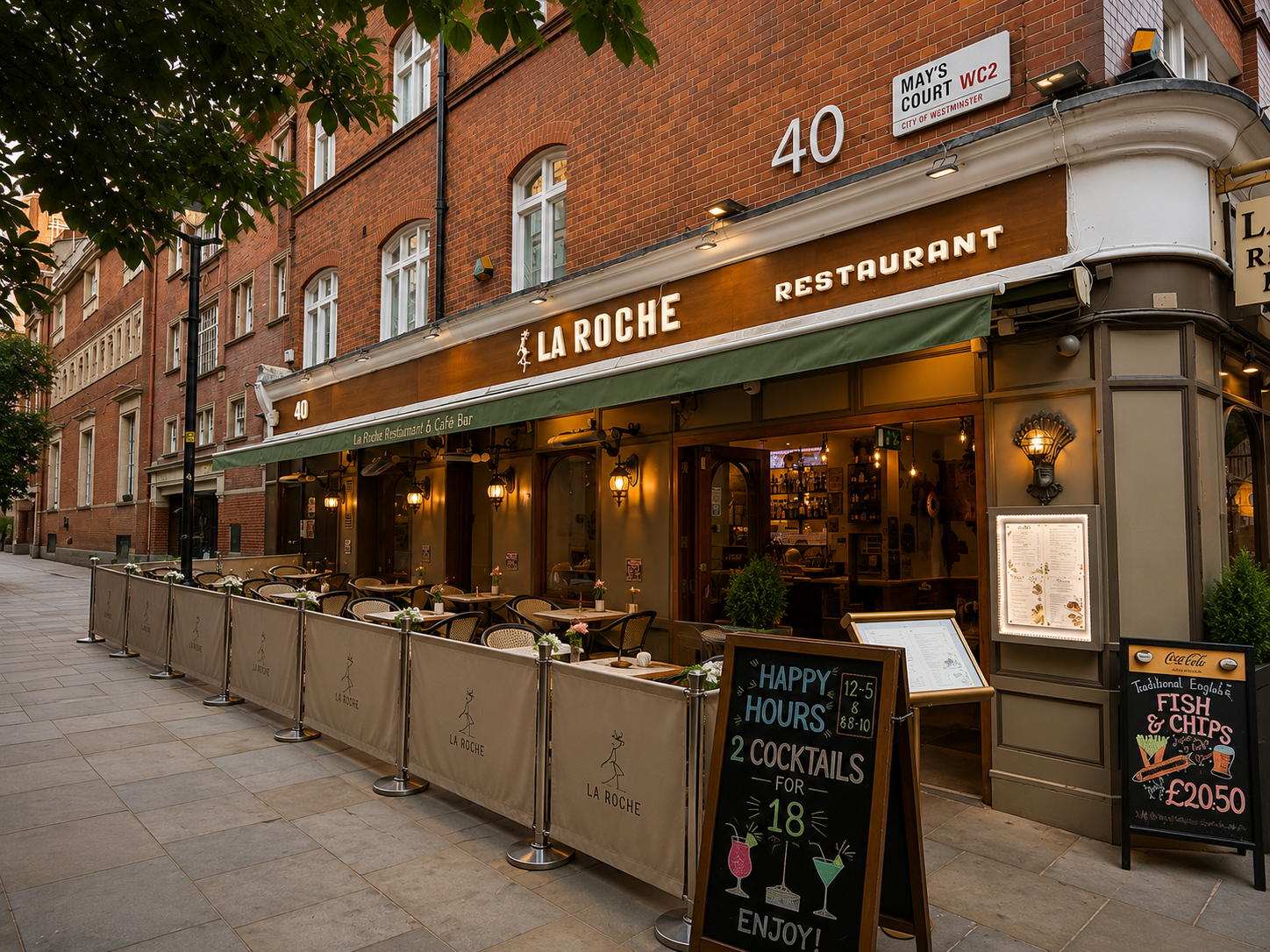 Exterior of La Roche restaurant with outdoor seating, sidewalk, and signage, located at 40 May's Court in Westminster, London.