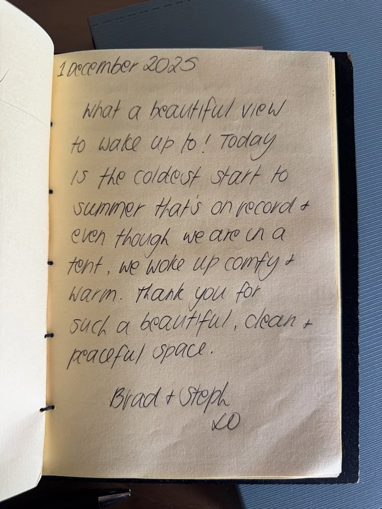 A handwritten note in a journal dated December 2025, expressing appreciation for a clean and peaceful space despite the cold start of summer, signed by Brad and Steph.