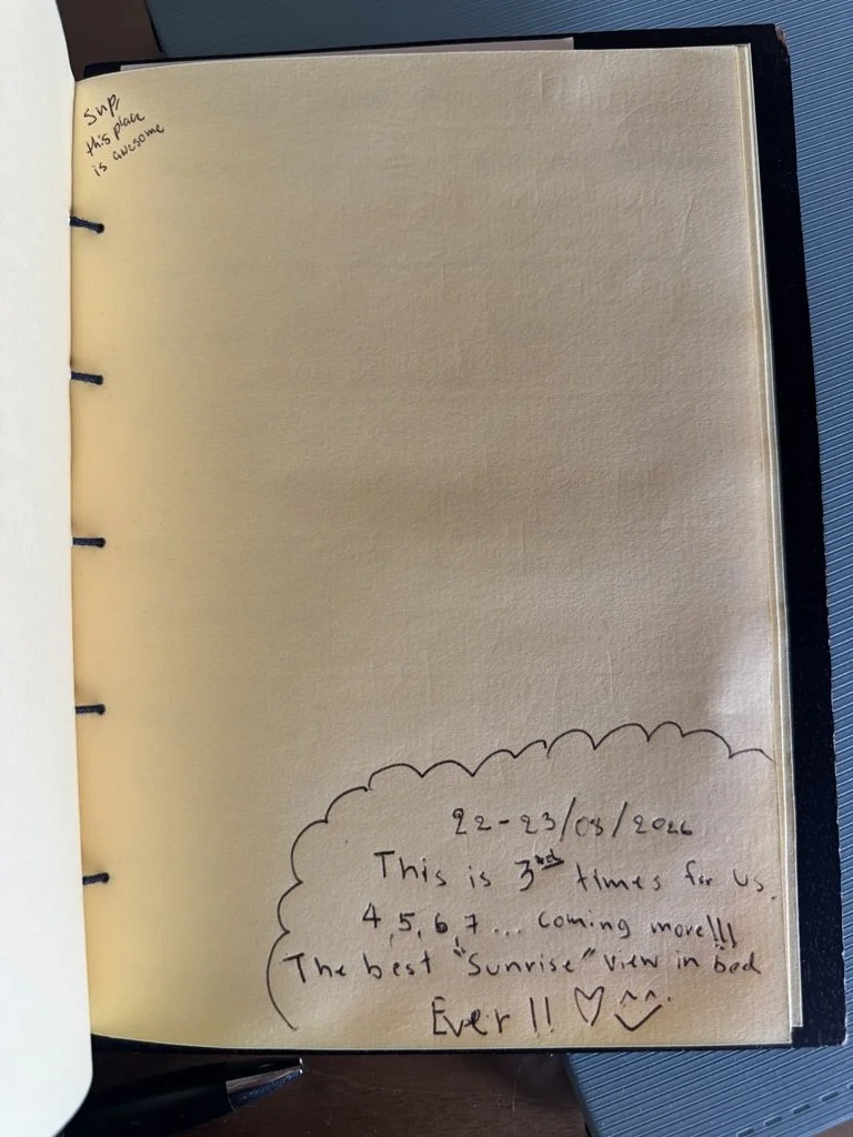 A notebook page contains handwritten notes that say, 'This is 3rd time for us, 4, 5, 6, 7... coming more!! The best 'Sunrise' view in bed ever!! ♥^.' The page also has a small handwritten note in the top left corner that says, 'Surp this place is awesome.'
