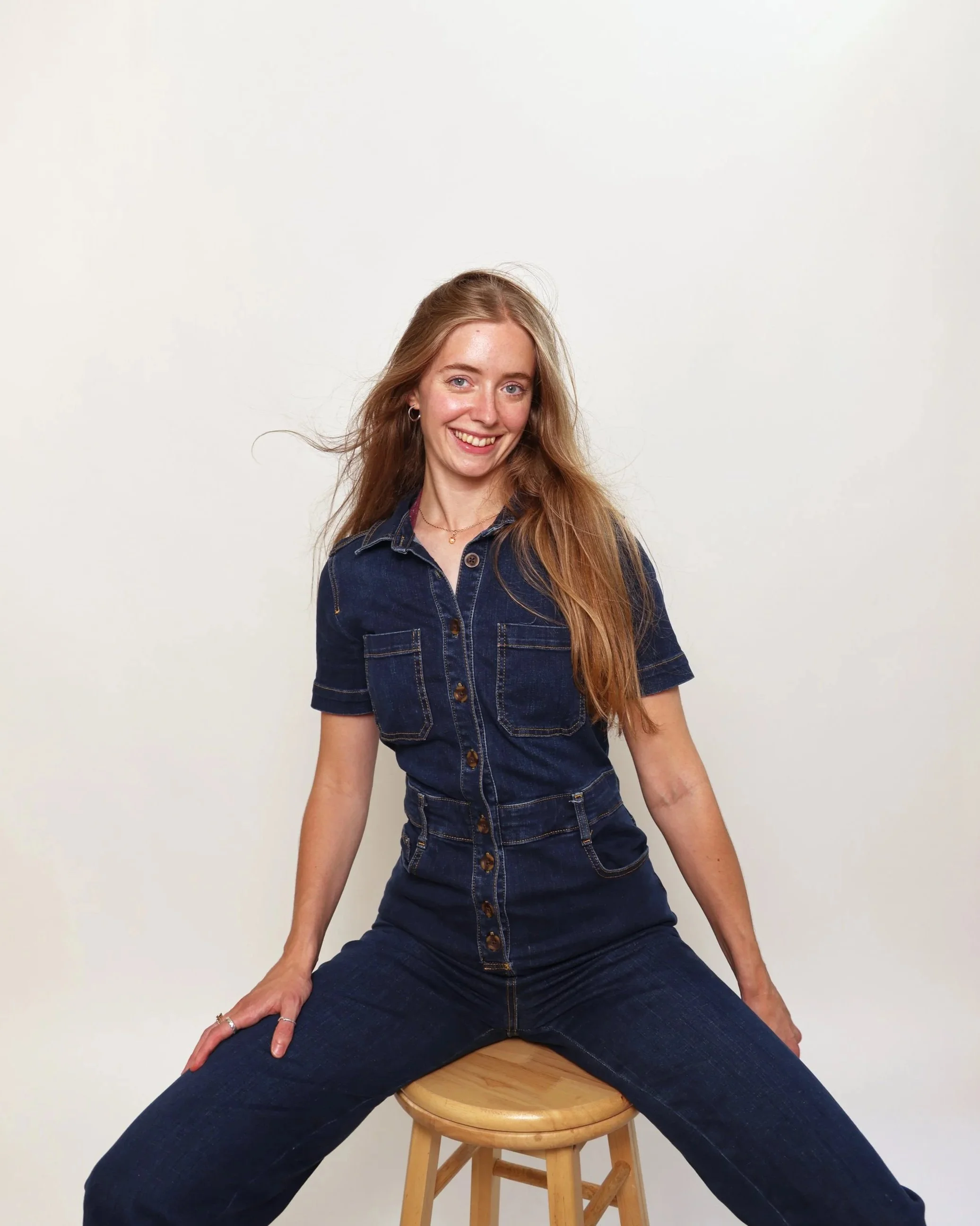 Victoria Sutton portrait wearing a blue denim jumpsuit on a white background