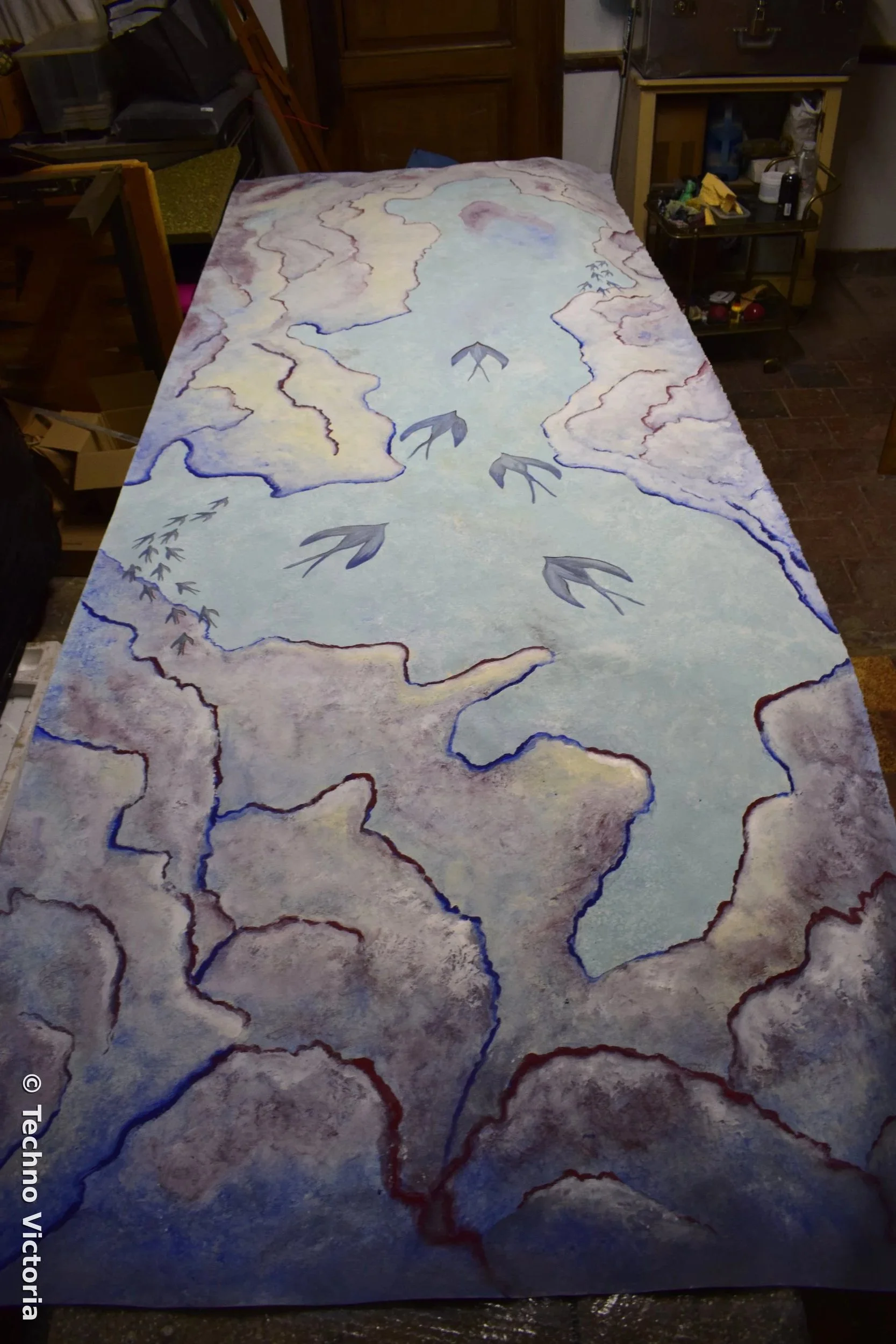 Fresco of birds and clouds by Victoria painting with raw pigments.