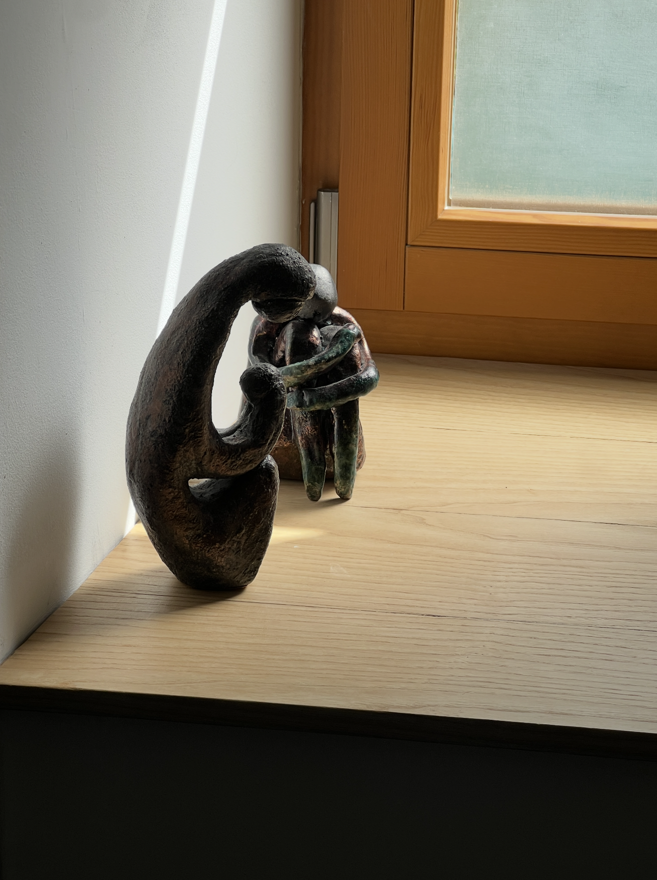 A decorative sculpture of a hand holding a bundle of keys, placed on a light wood surface near a window with wooden framing.