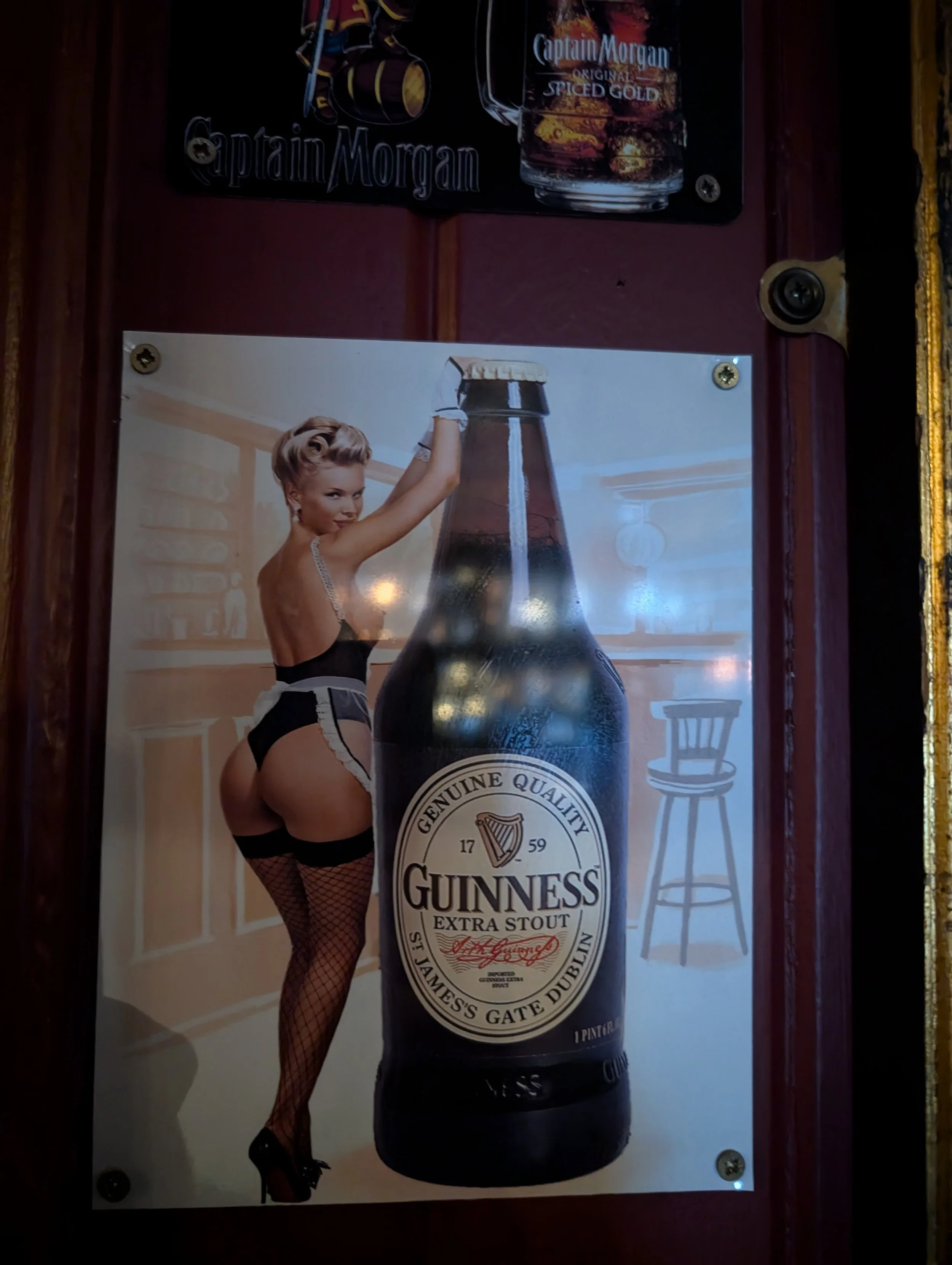 A vintage-style poster of Guinness beer featuring a woman in fishnet stockings and black lingerie, holding a large Guinness bottle and posing provocatively.