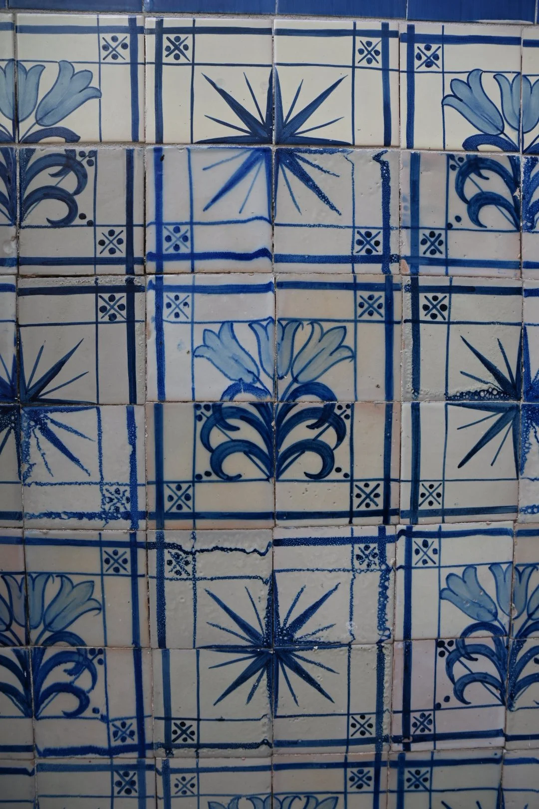 Close-up of a wall decorated with traditional blue and white ceramic tiles featuring floral and starburst patterns.