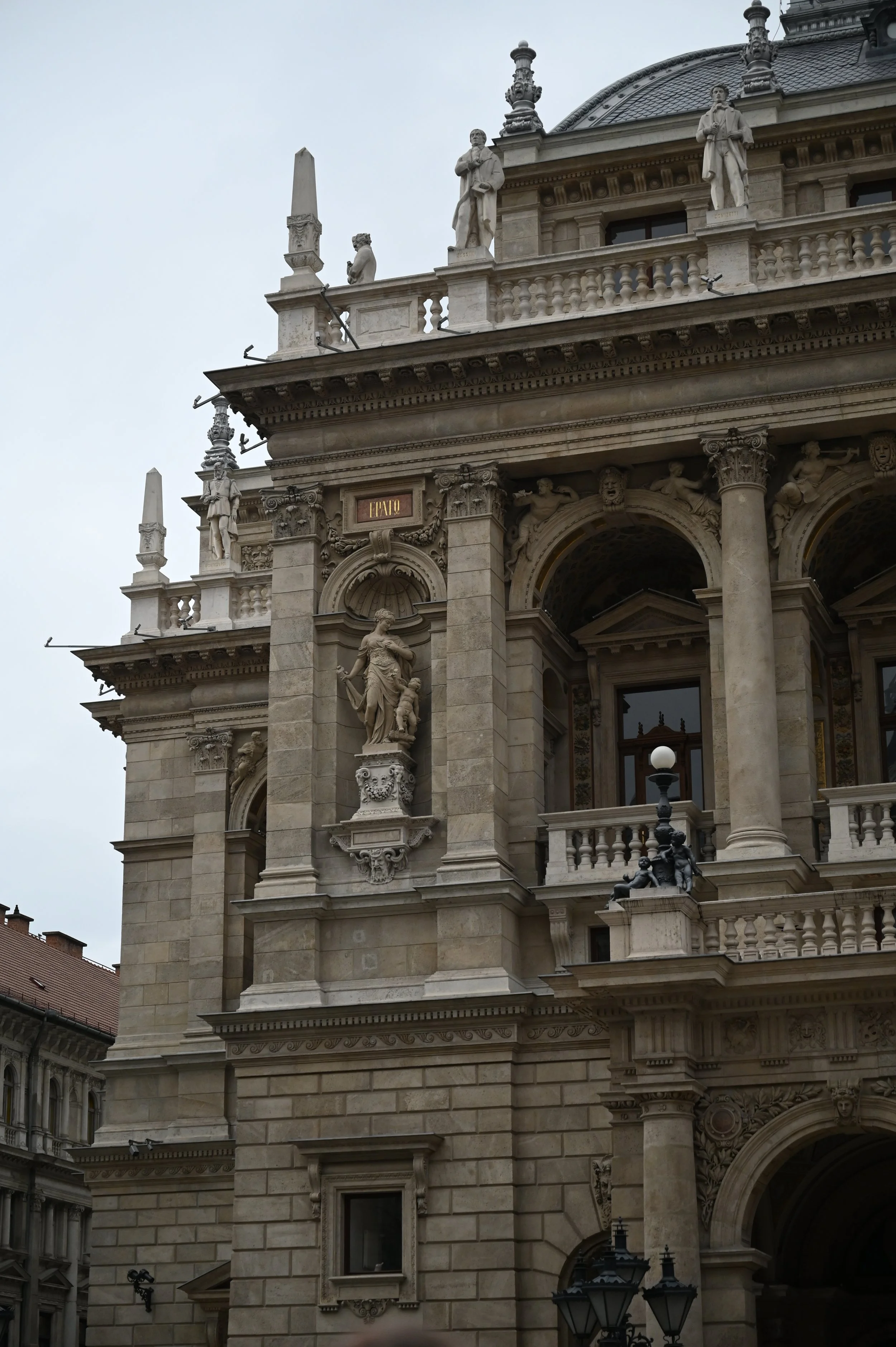 Close-up of a historic building with ornate statues and architectural details, including columns, balustrades, and decorative sculptures on the facade.
