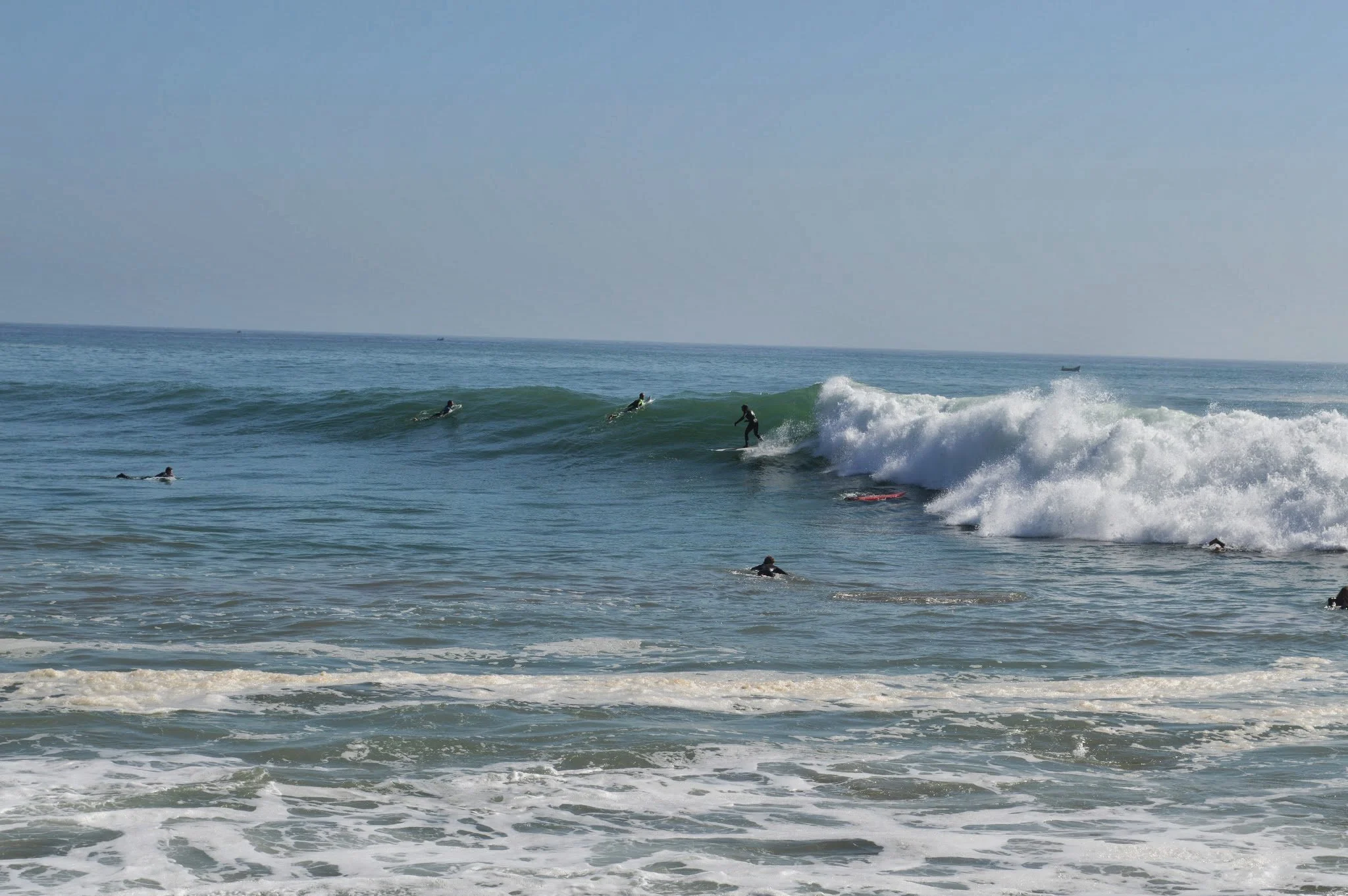 People surfing on waves near the shore on a clear day.