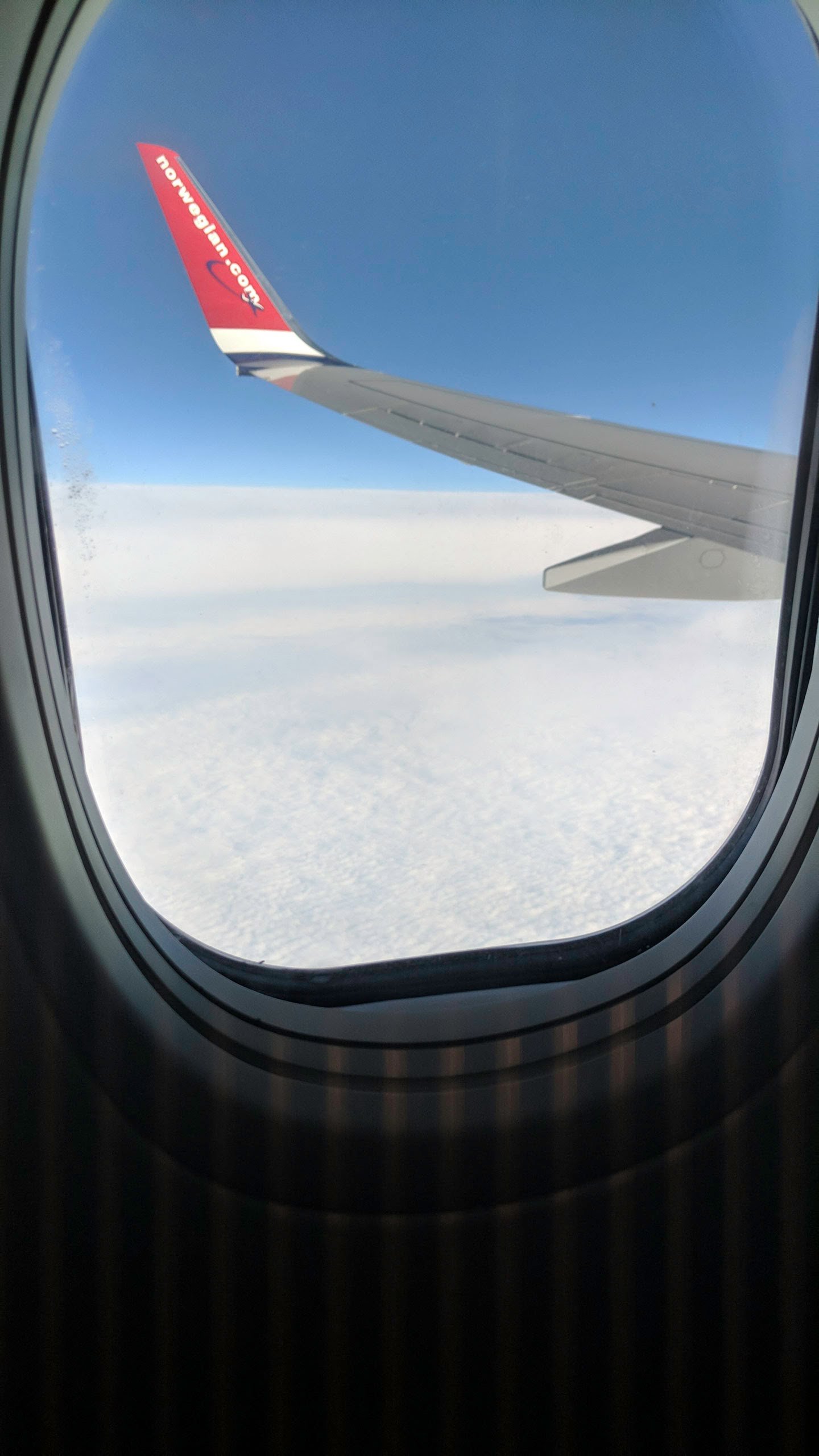 View of a plane wing and sky outside the airplane window.