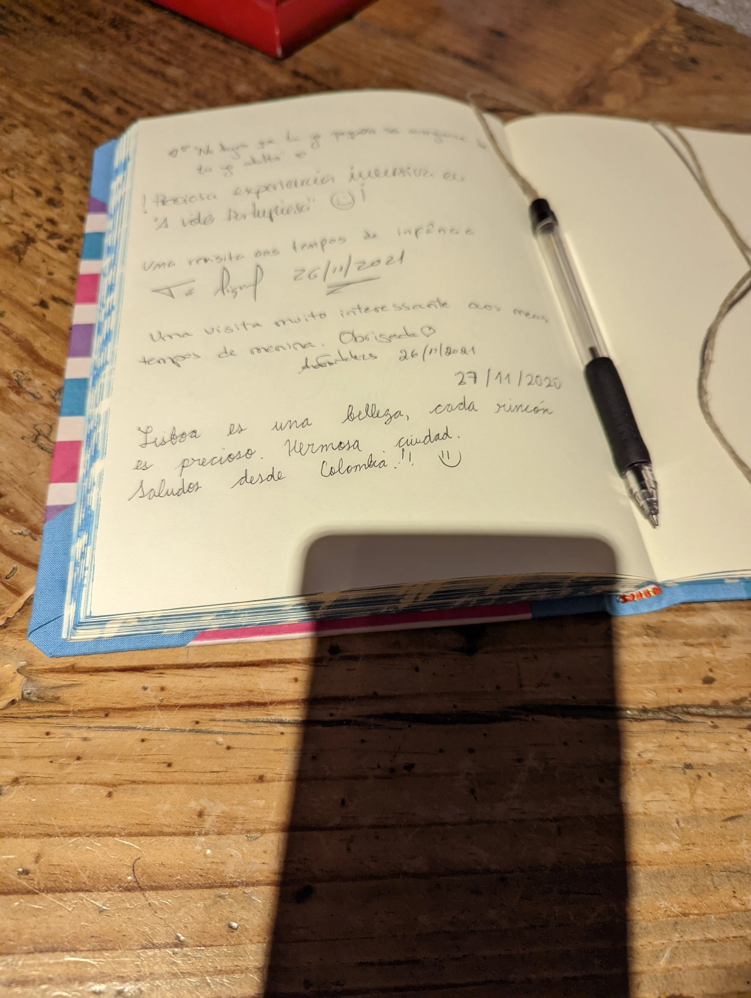 Open notebook with handwritten notes in Spanish, black pen resting on the right page, on a wooden table.