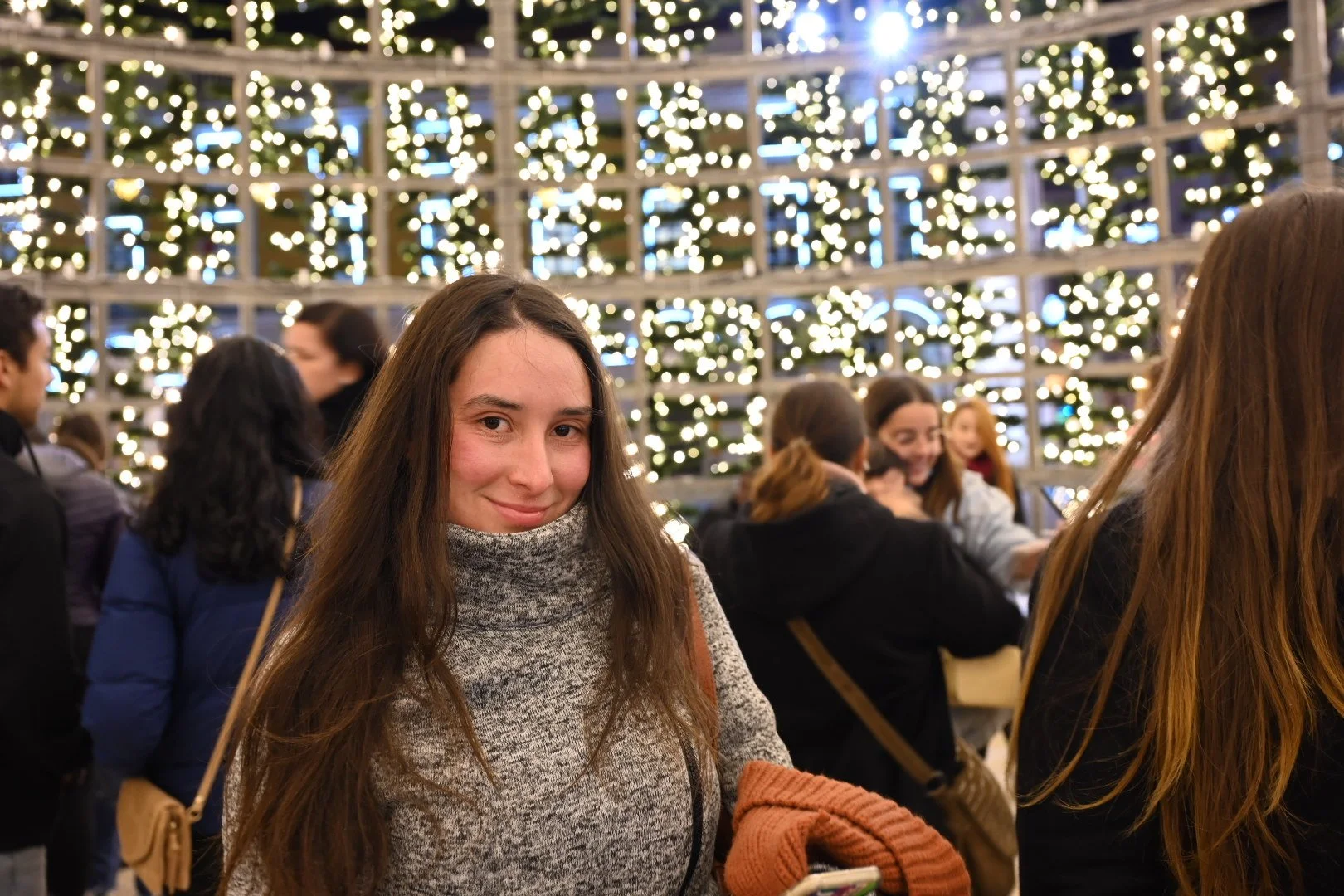 Women at a holiday gathering with Christmas lights in the background.