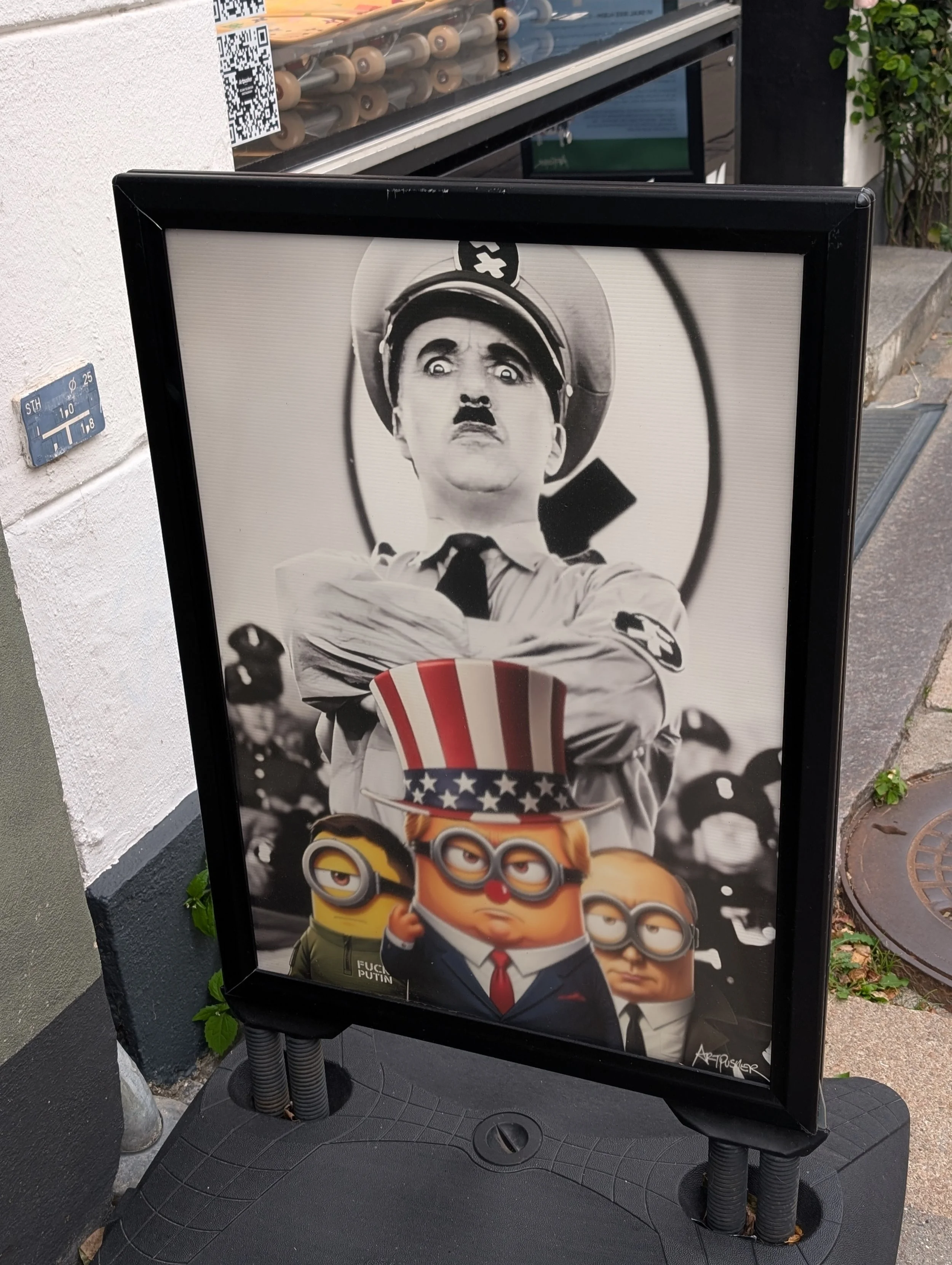 A black-and-white poster featuring a person in a uniform and cap with a shocked or stern expression, holding a large patriotic-themed top hat, with animated characters from the movie Minions below.