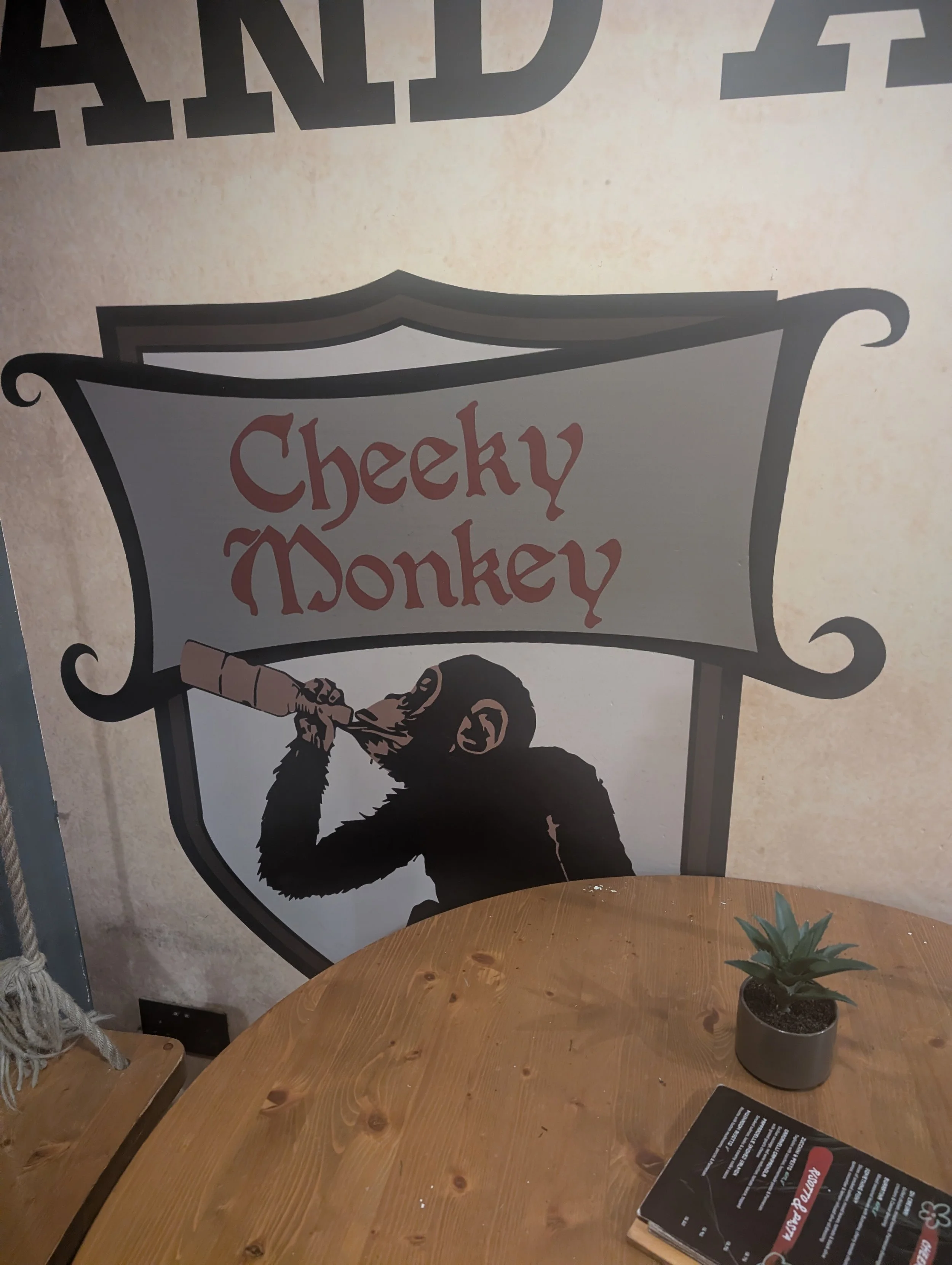 A poster displays a cartoon image of a chimpanzee smoking a cigar with a banner that reads "Cheeky Monkey."