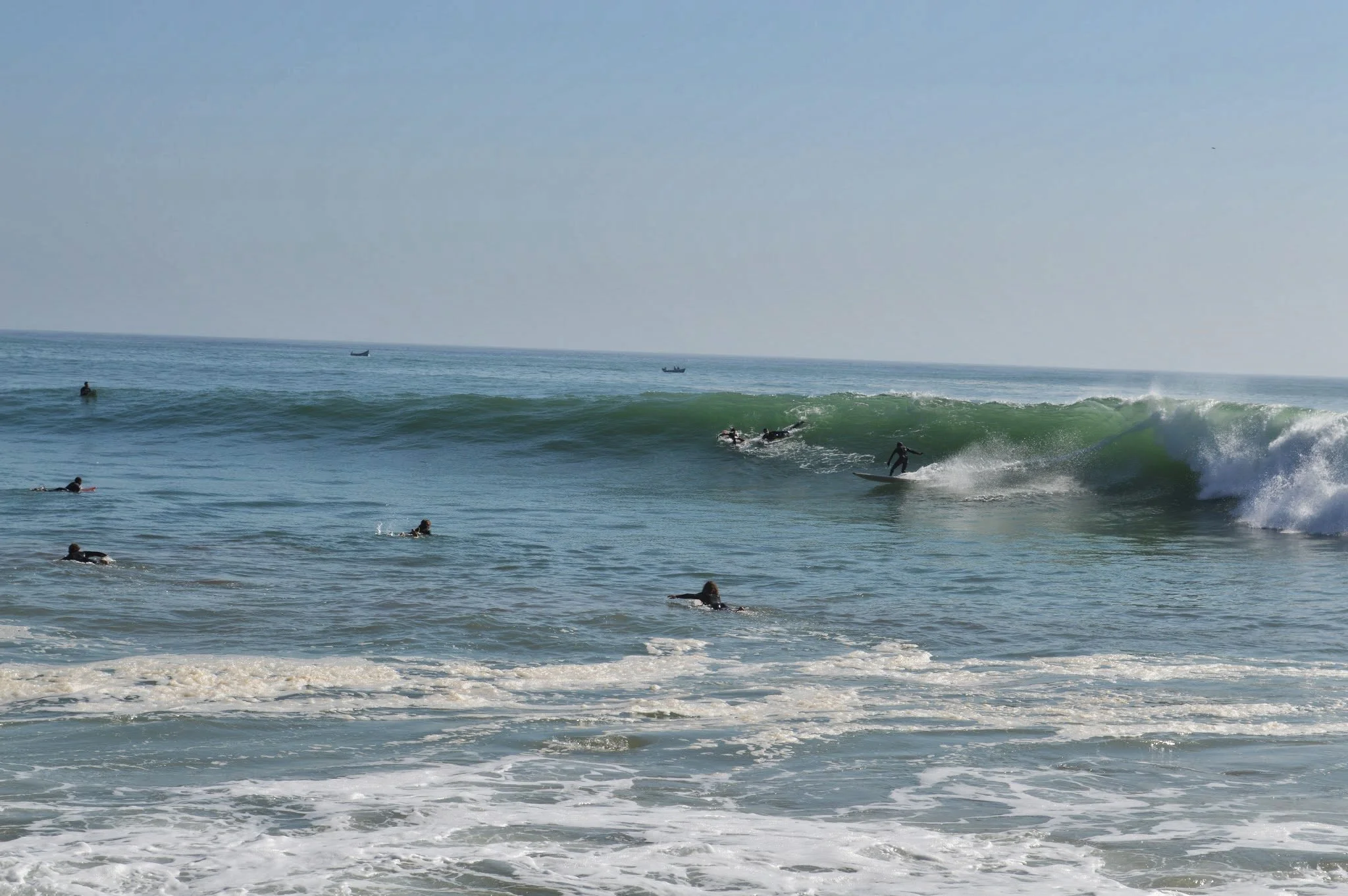 People surfing and swimming in the ocean near the shore during daytime.