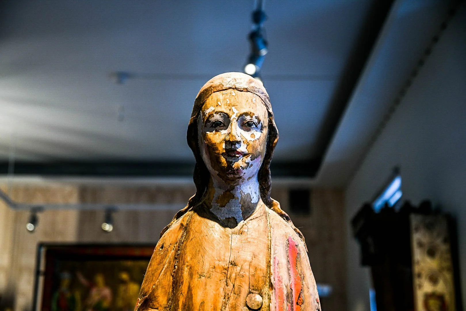 Close-up photo of a vintage wooden religious statue of Jesus Christ with a serene expression, in an indoor setting.